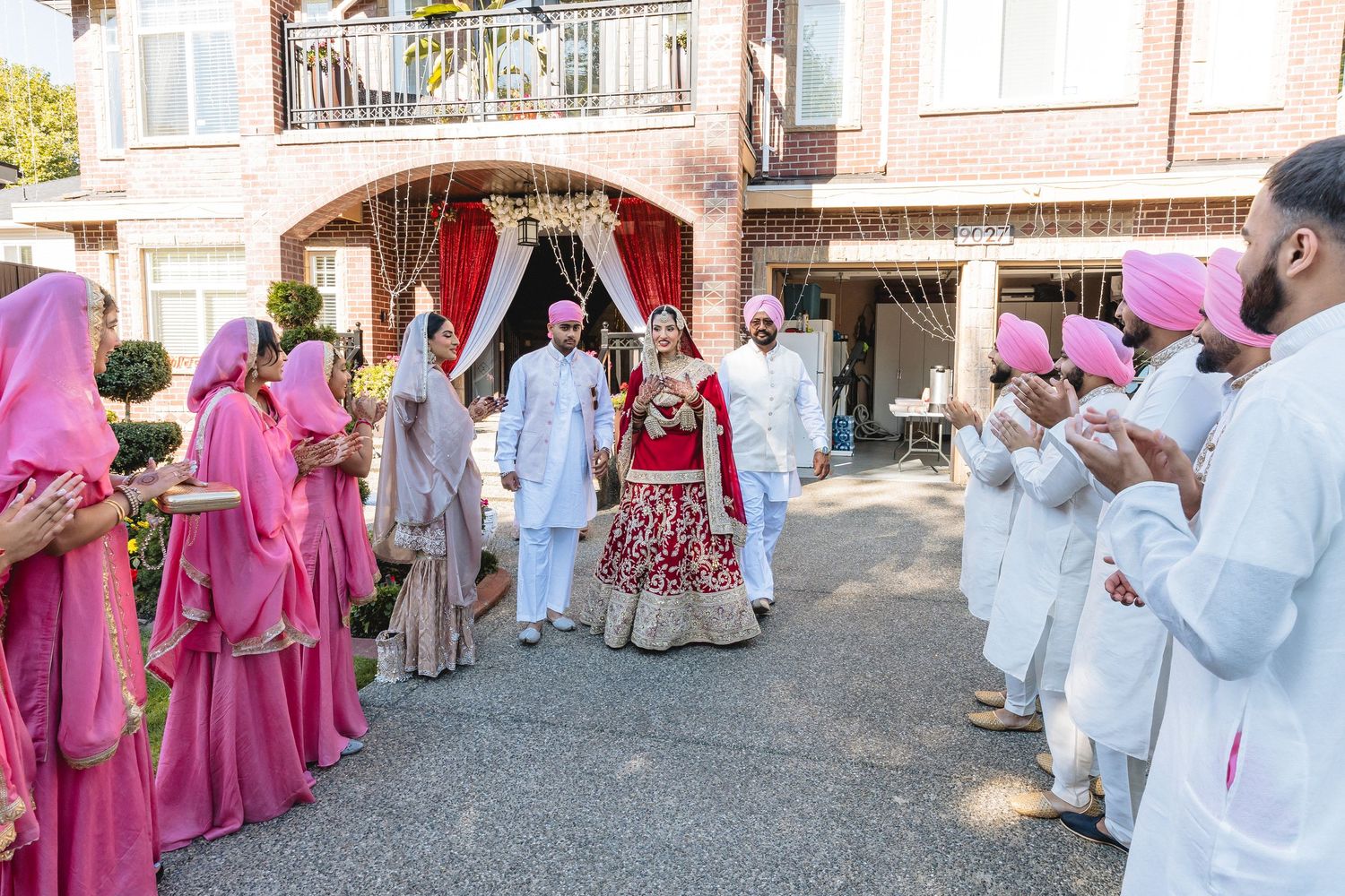 Wedding guests in pink and white attire gathered outside a venue during a celebration.