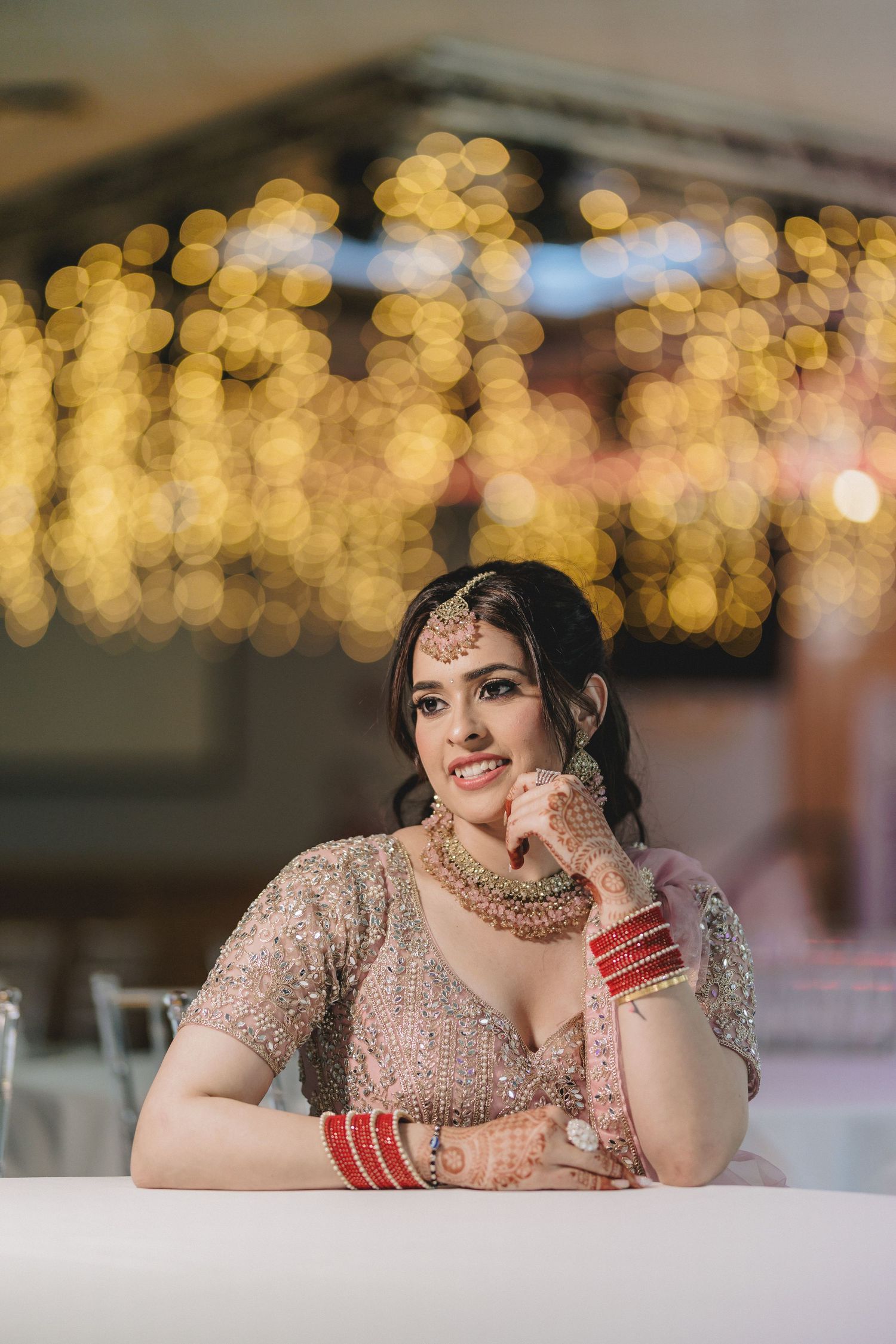 Ornate bridal jewelry and makeup details captured with soft bokeh lighting effects in the background.
