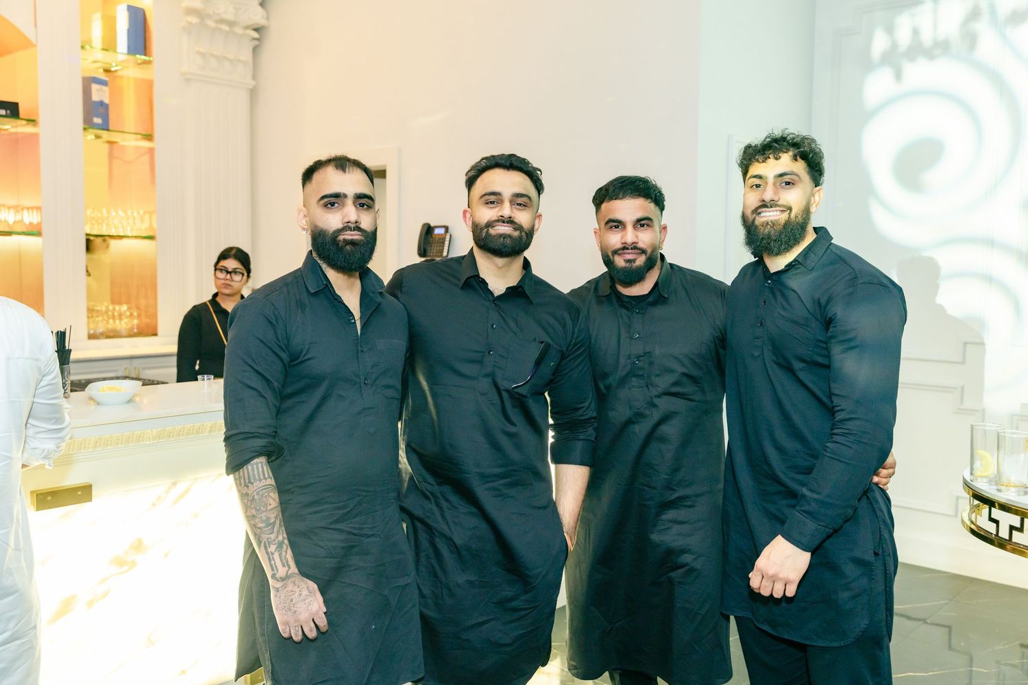 Group of men wearing coordinated black formal attire posing together at an event.