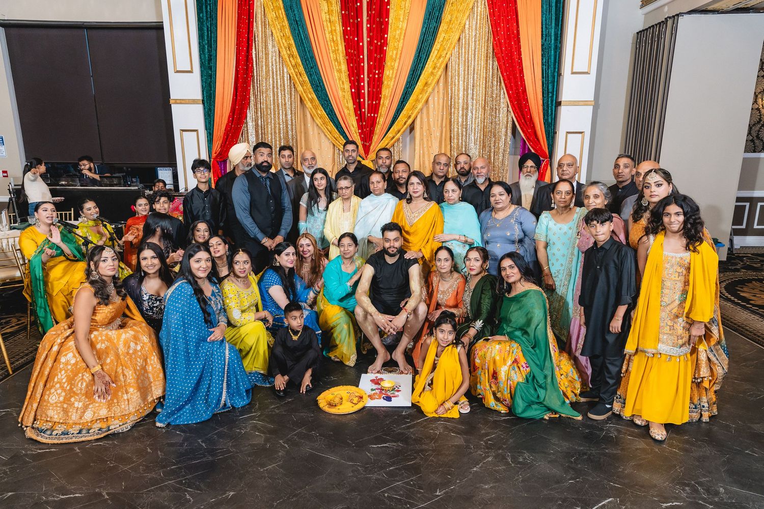 Large group photo showing colorful traditional Indian attire and decorations at a cultural celebration event.