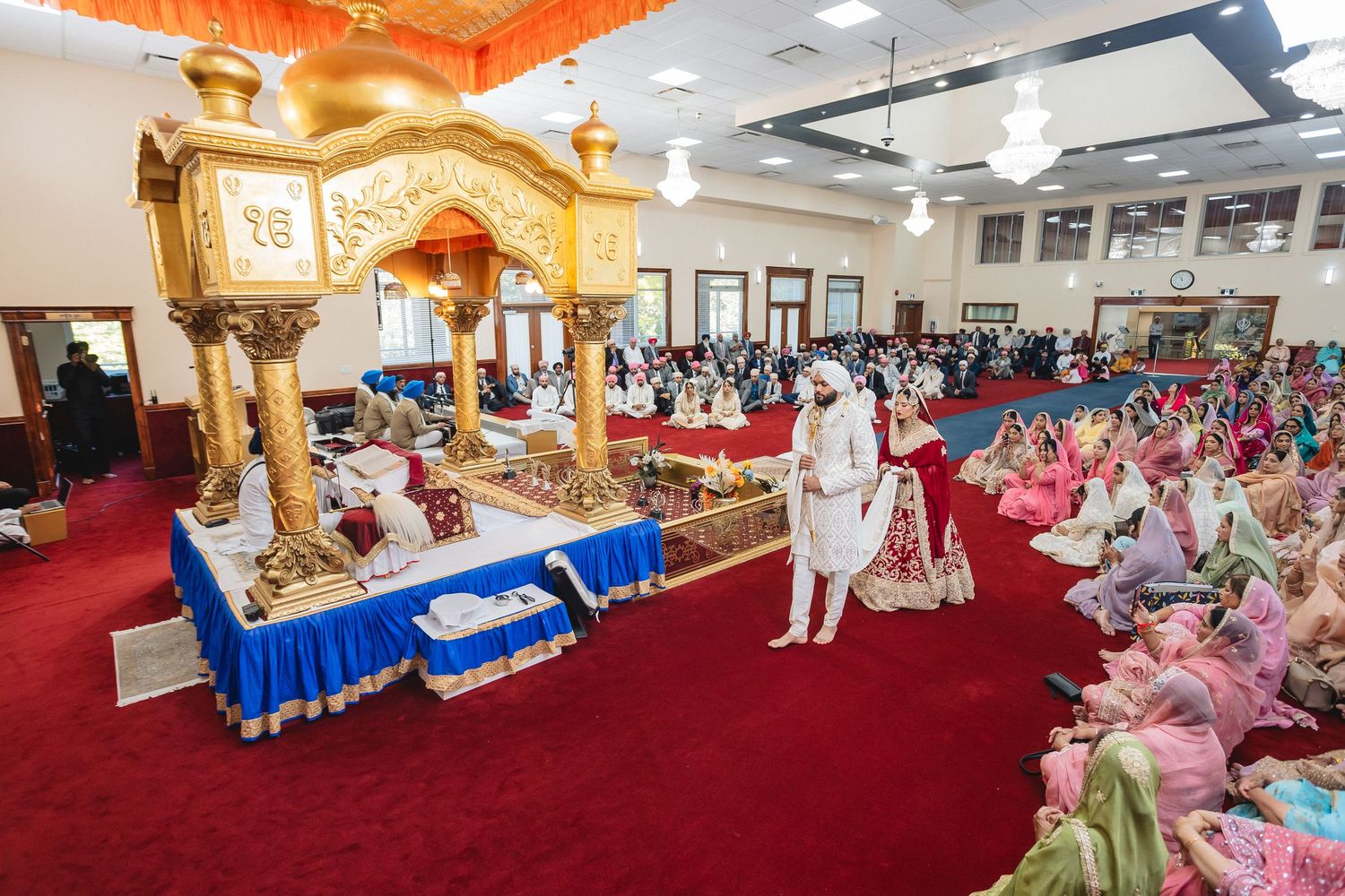 Large indoor wedding ceremony venue with red carpet and decorative elements.