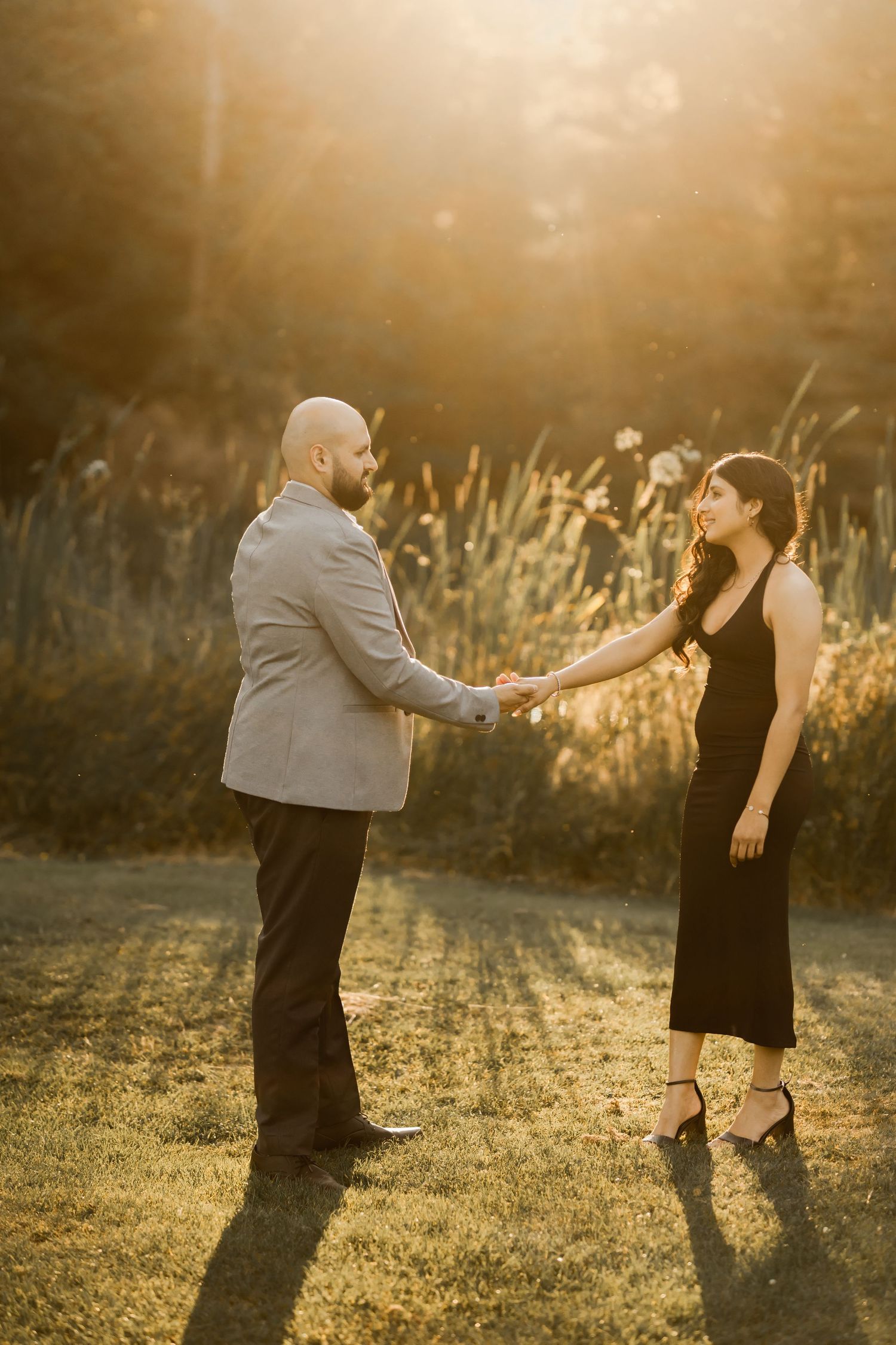 A couple dances in a sun-lit field during a golden hour photo session.