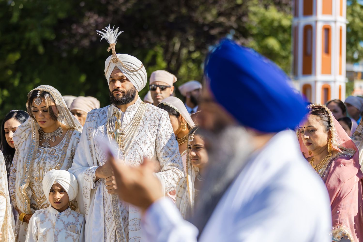 Outdoor gathering of guests in traditional Sikh attire with turbans and formal wear.