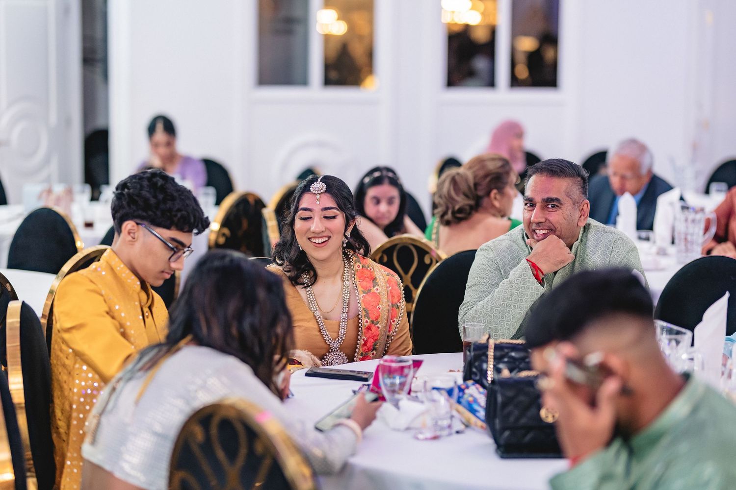 Wedding reception venue with guests seated at decorated tables during an indoor celebration.