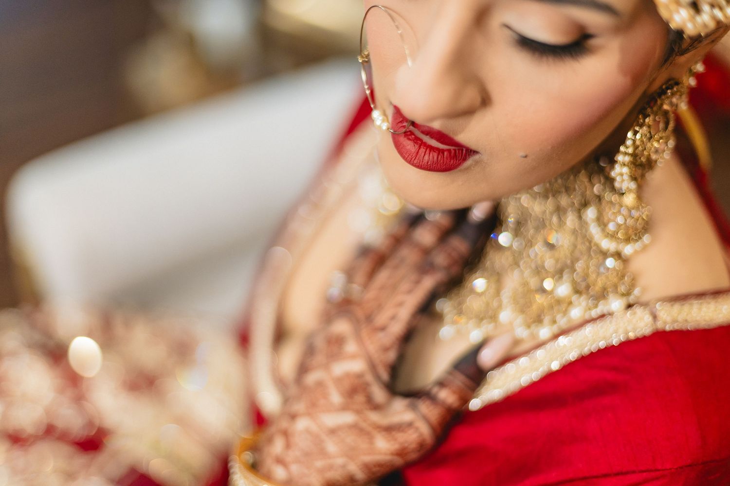 Close-up details of bridal jewelry and traditional henna designs in rich gold and red colors.