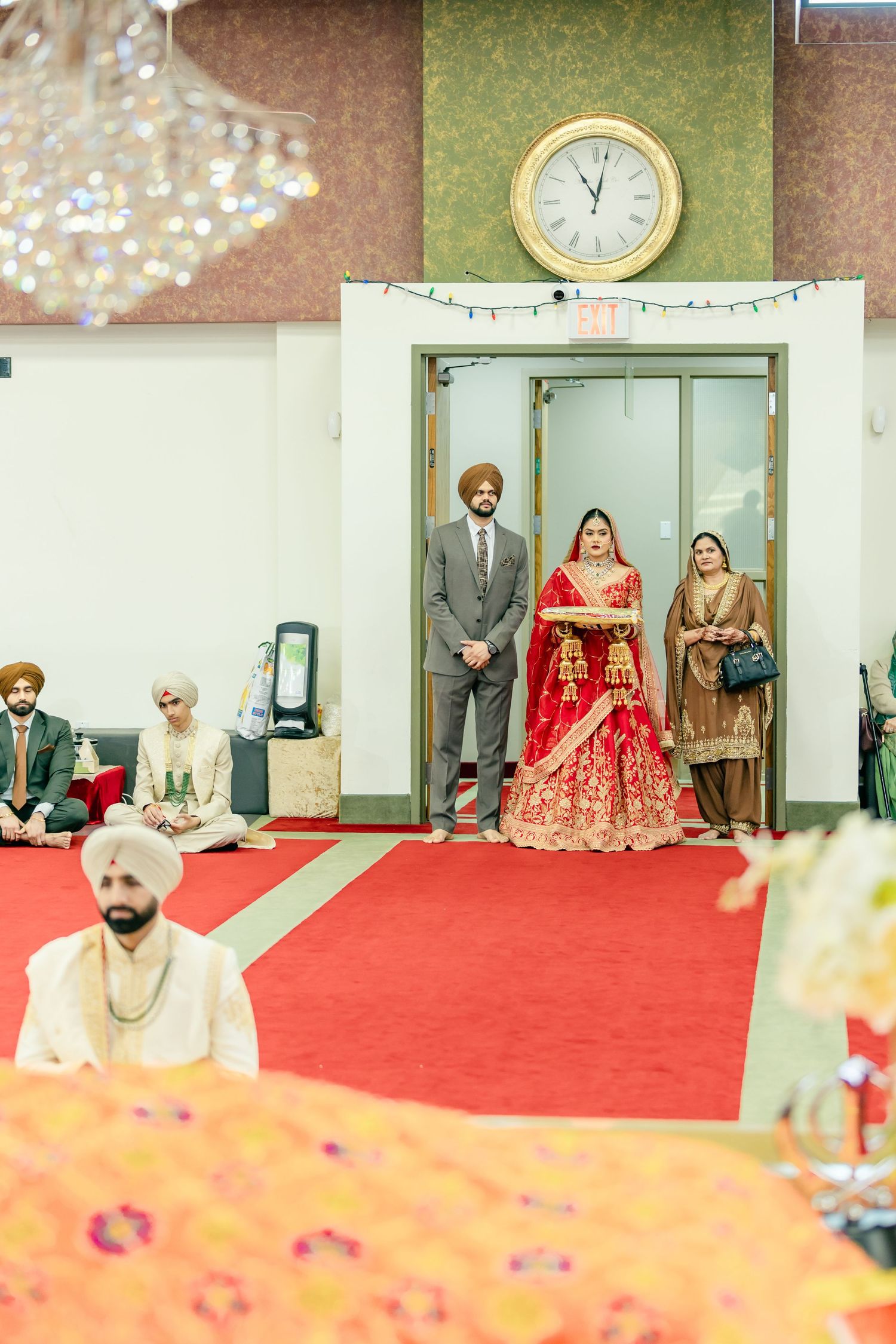 Wedding ceremony in progress with red carpet and decorative lighting.