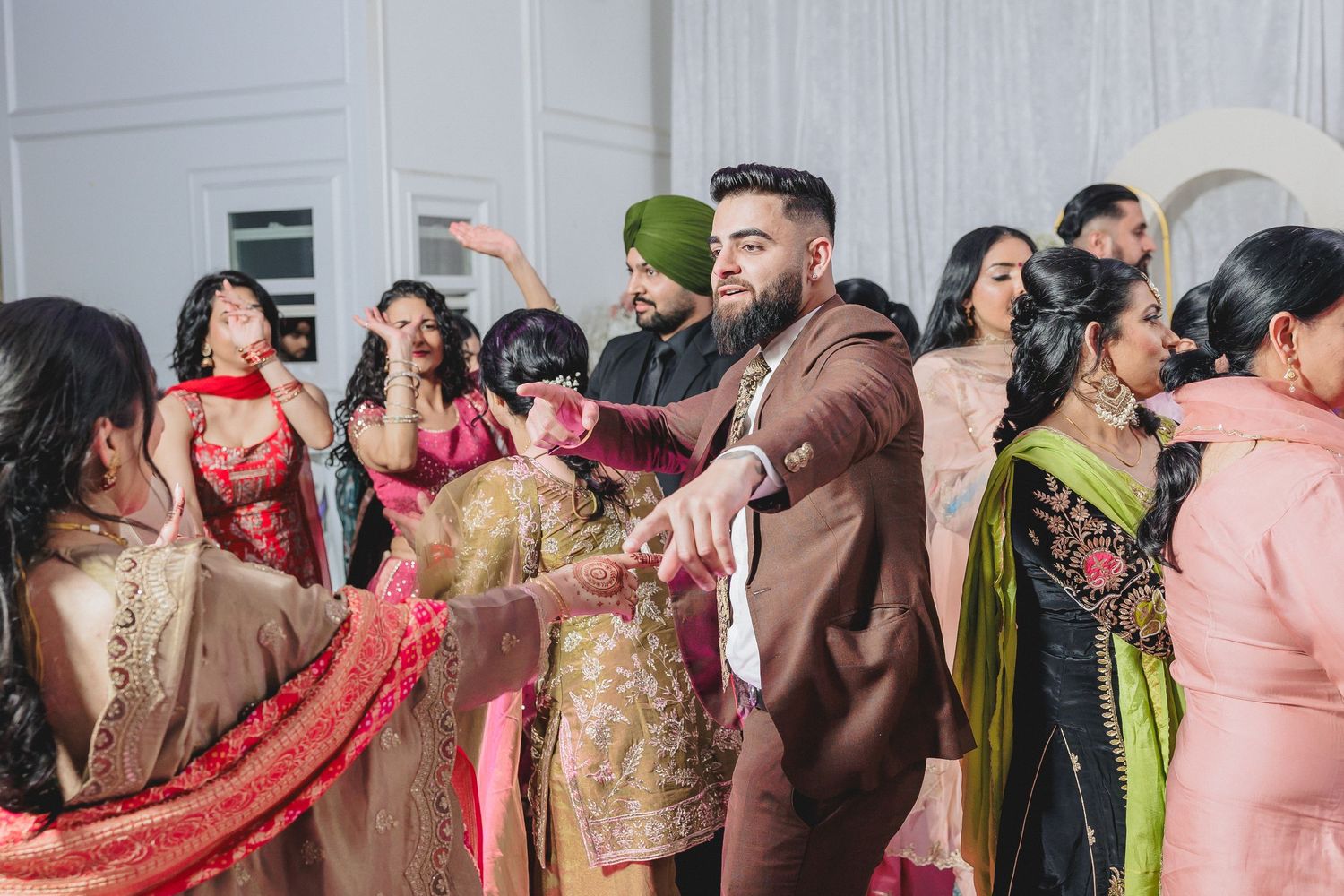 Group photo of celebration attendees in traditional Indian clothing against white backdrop.