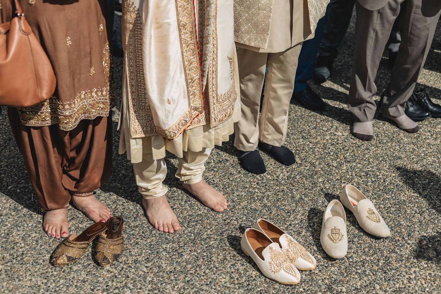 Various wedding guests' feet and shoes visible on gravel ground.