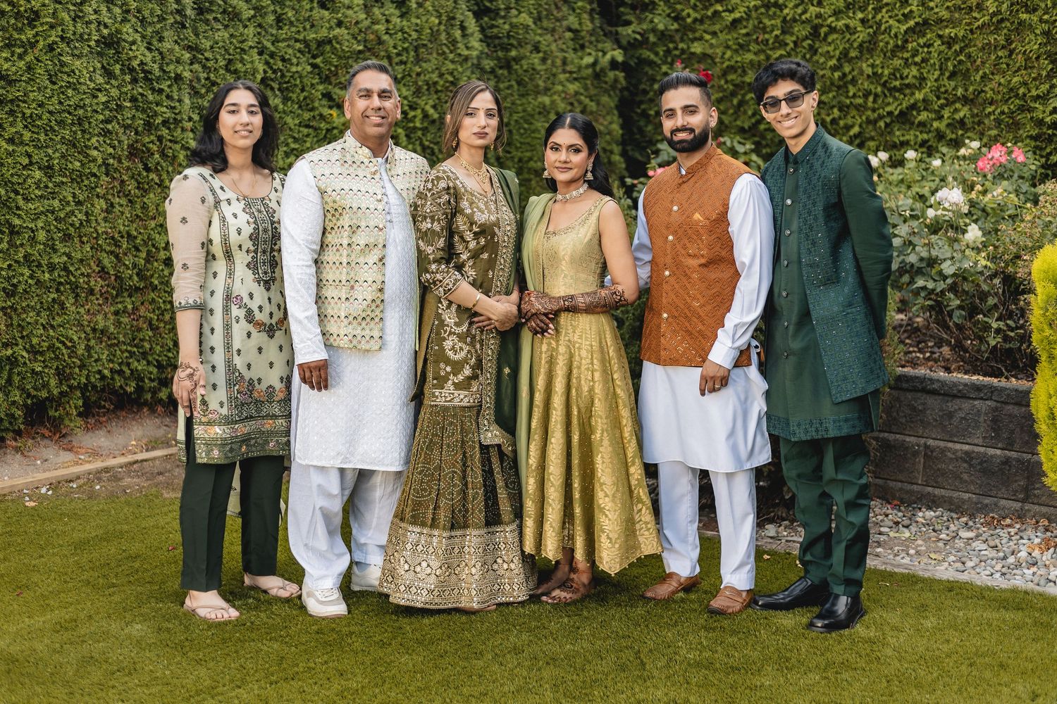 Group photo of guests in traditional Indian formal wear standing together in a garden setting.