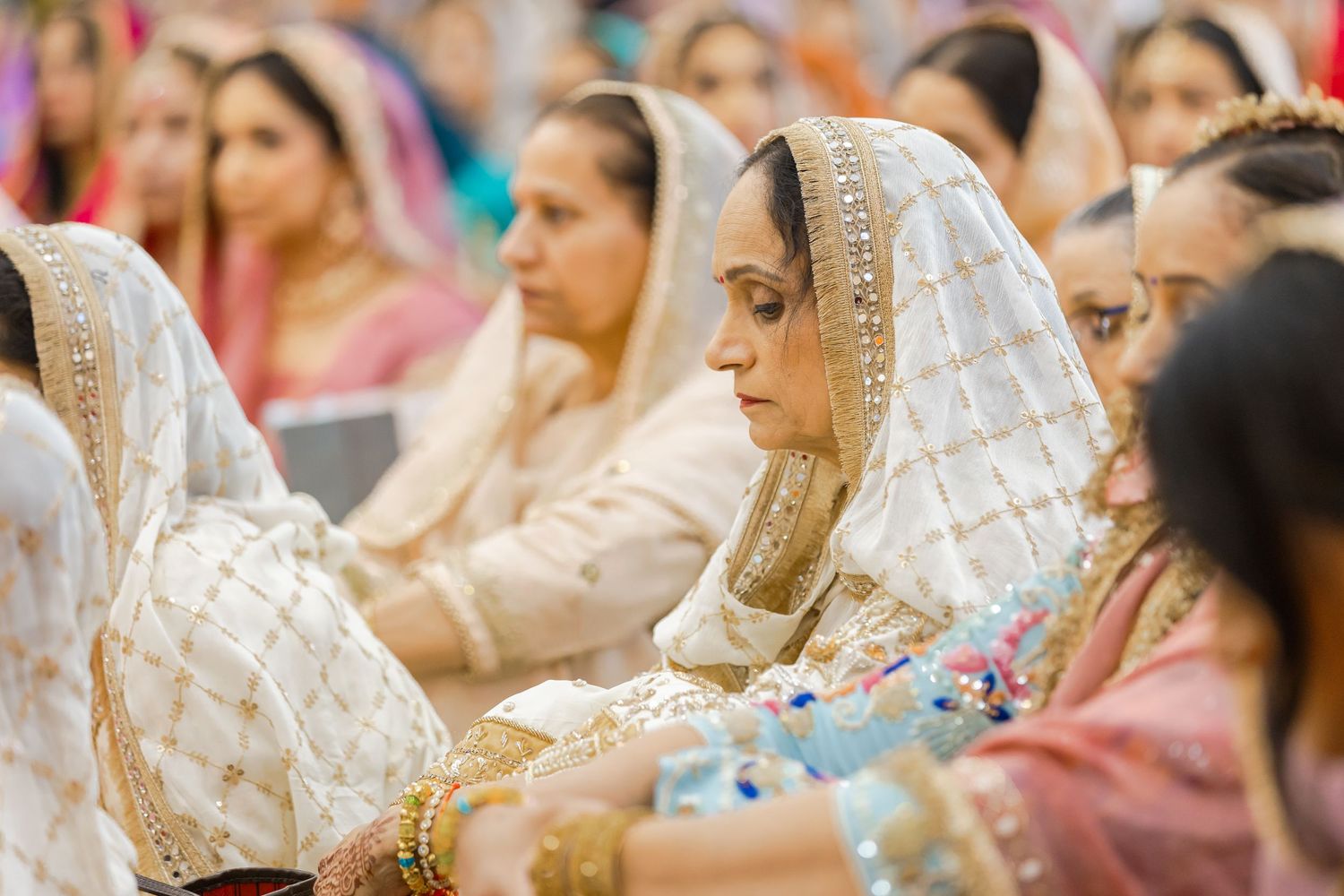 Wedding ceremony attendees seated in traditional attire with decorative head coverings.
