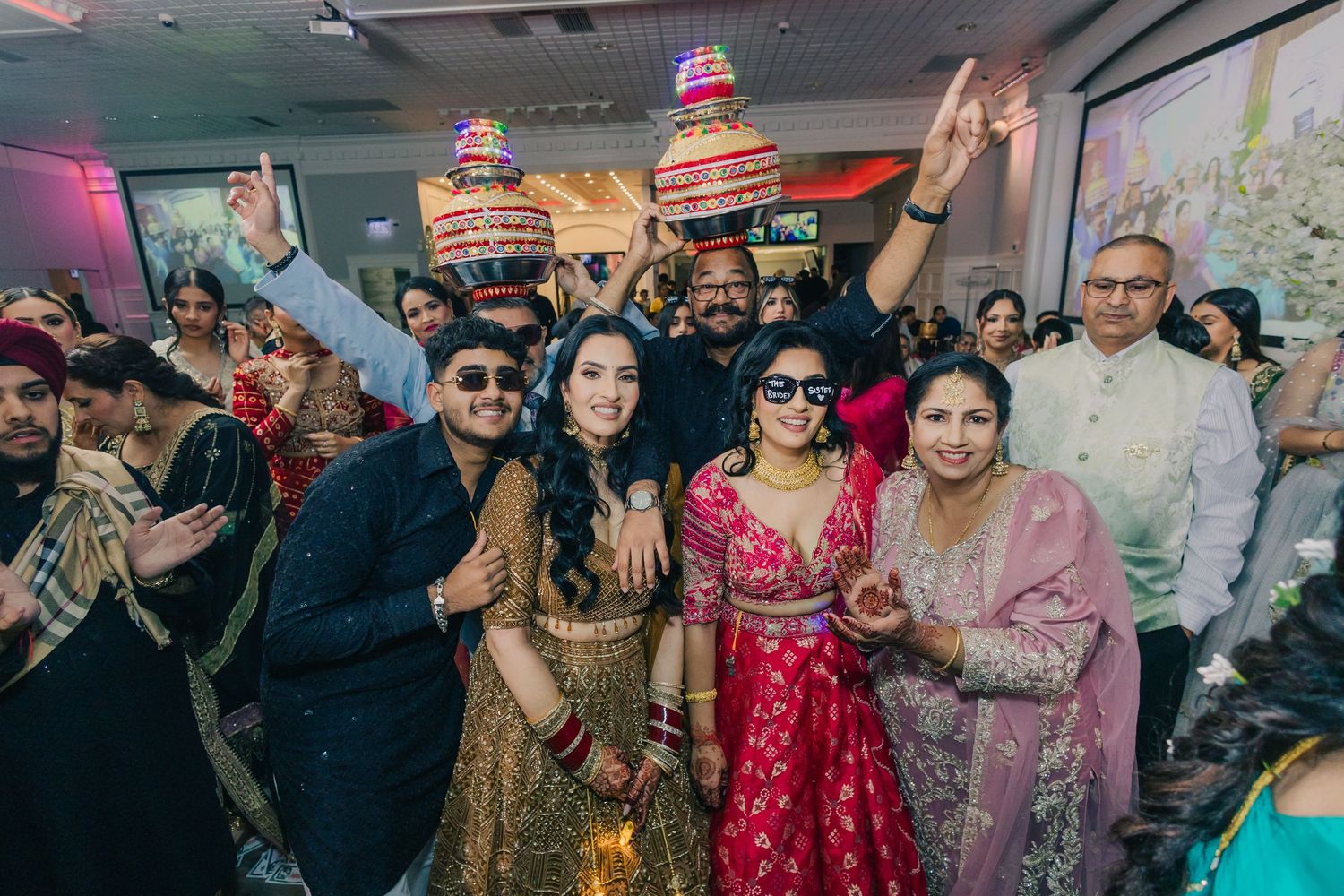 Large group of wedding guests celebrating and dancing together at a festive reception.