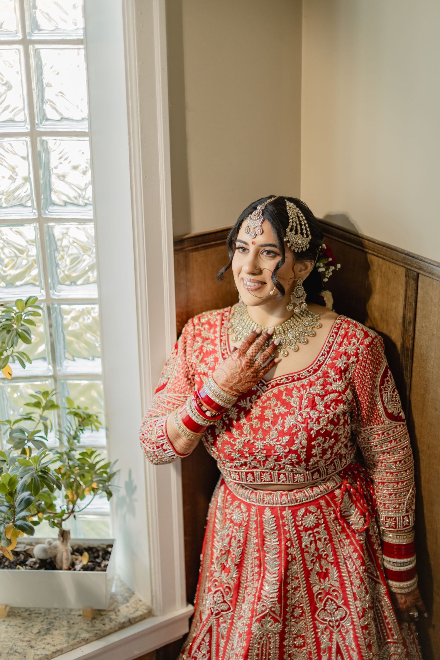 Traditional Indian bridal outfit in red and gold photographed by window light.