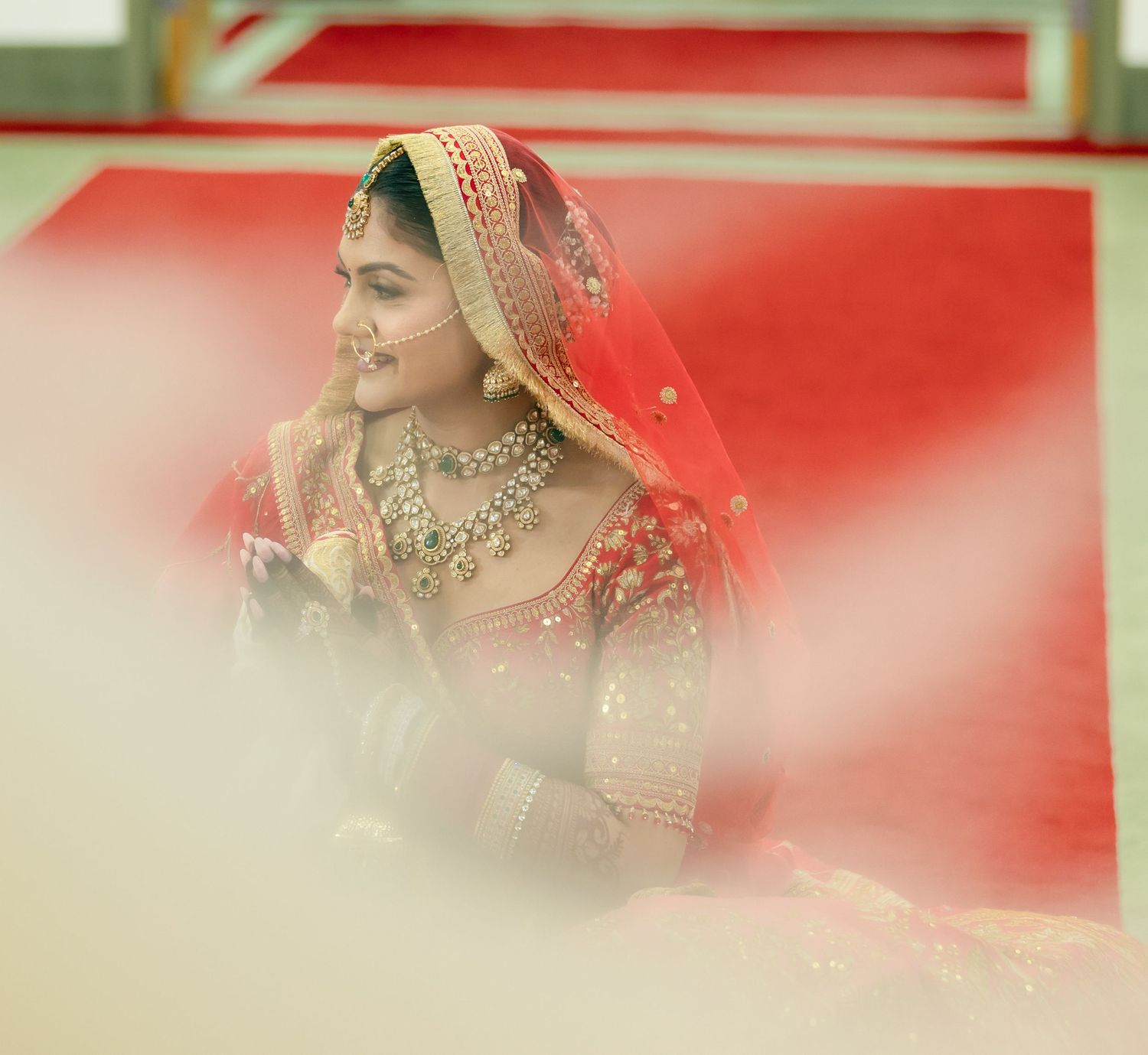 Artistic wedding photography with soft focus and red tones capturing traditional Indian bridal details.