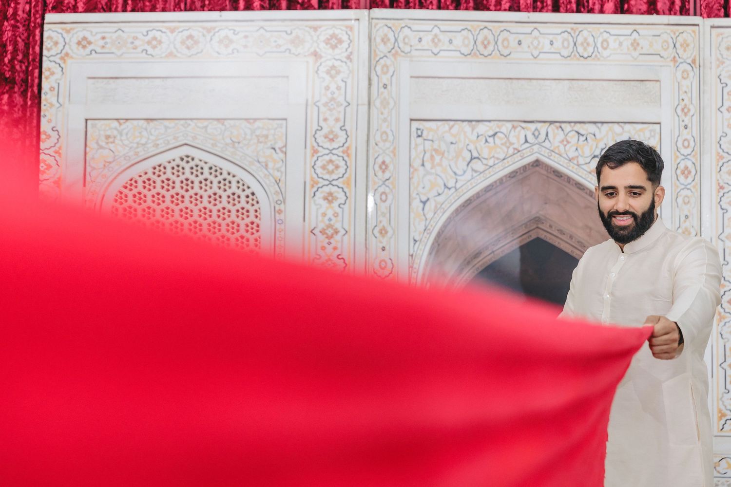 Ornate red and white decorative elements against a traditional patterned background.