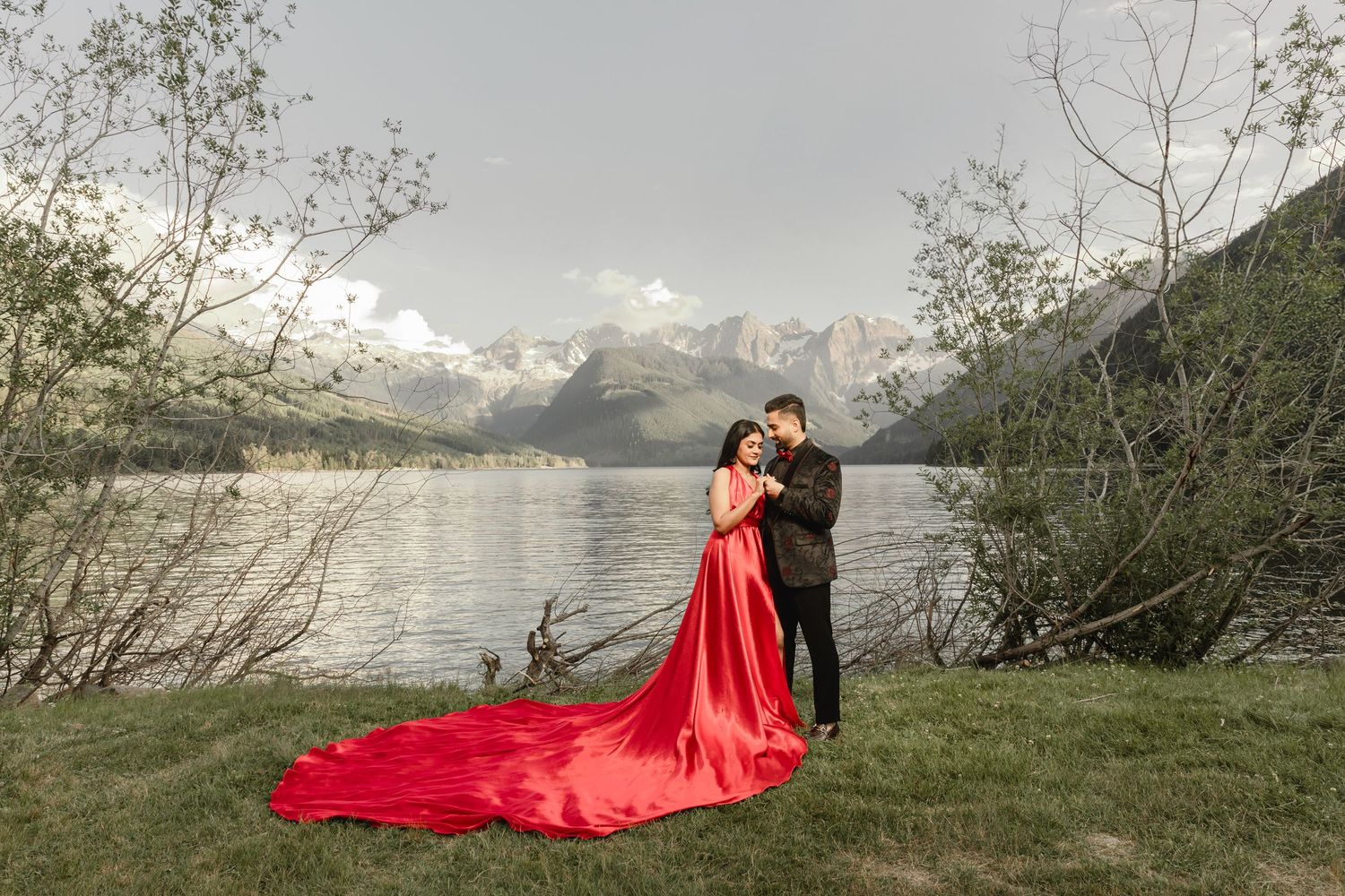 Dramatic photo series with flowing red dress against mountain and lake backdrop.