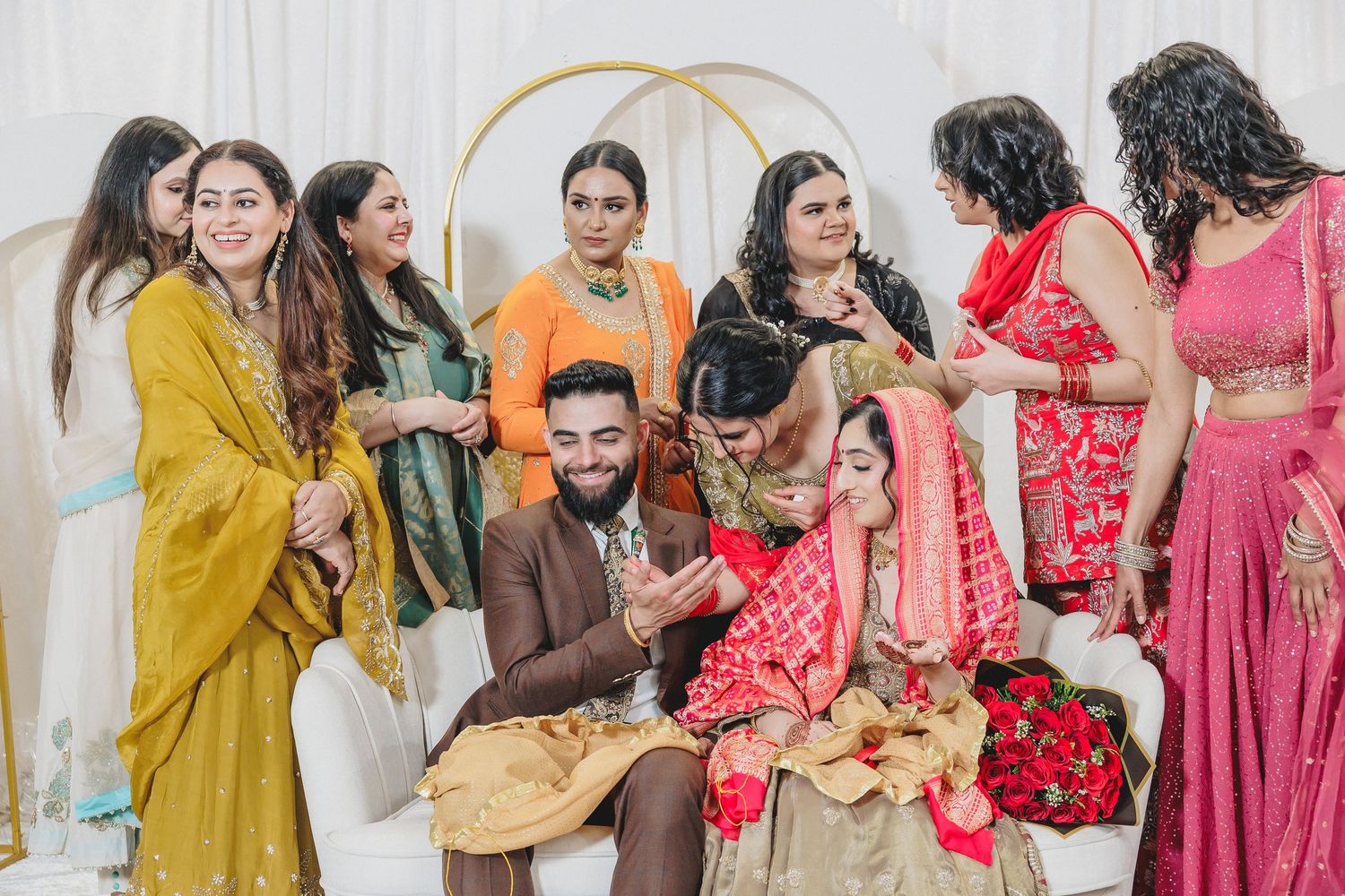 Guests in colorful traditional Indian attire gather at a celebration event with decorative backdrop.