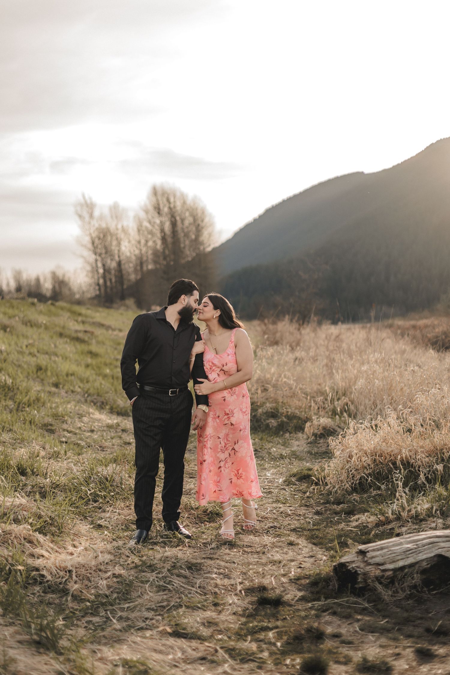 Two people share a romantic moment on a mountain trail during golden hour.
