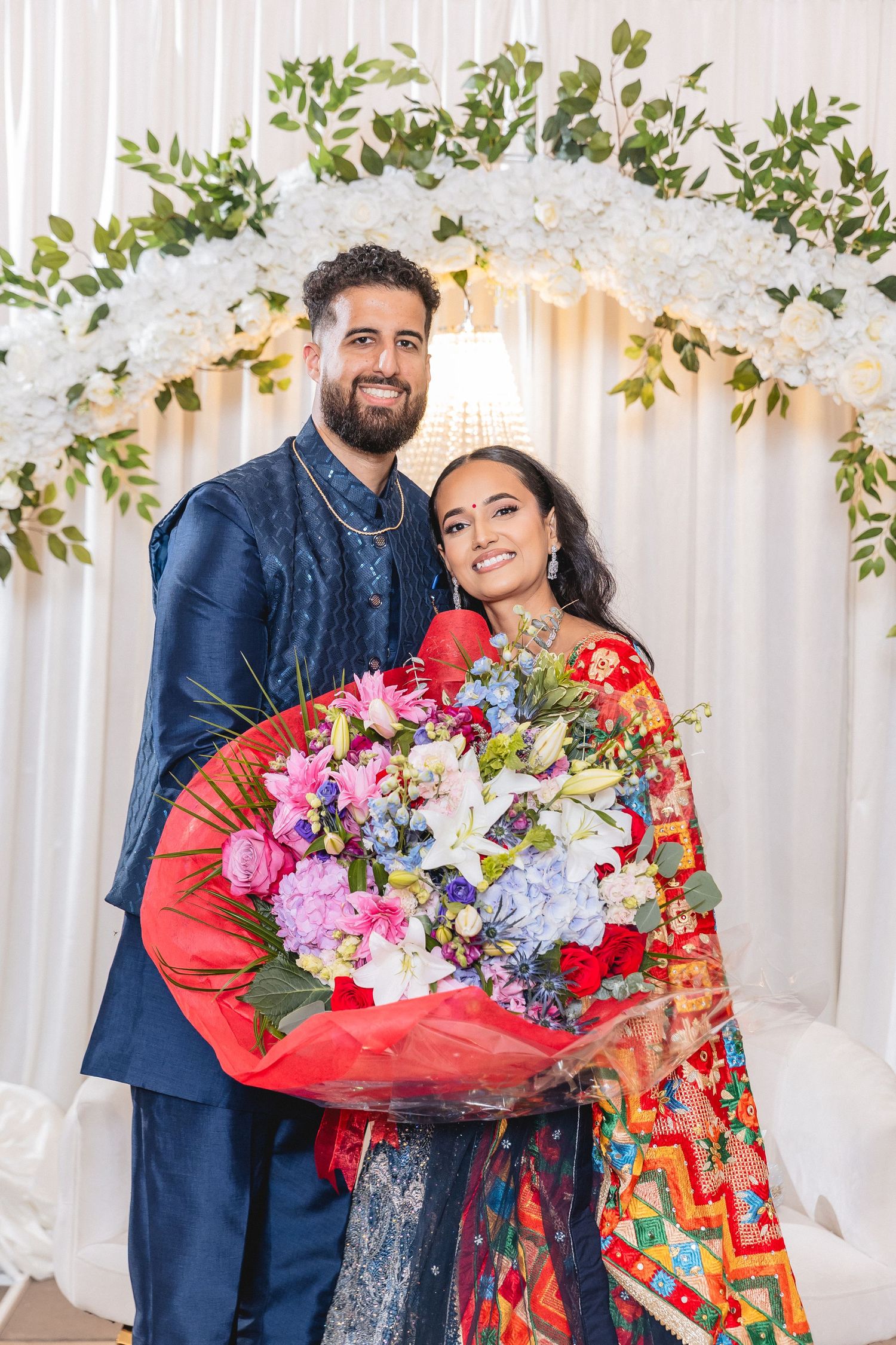 Celebratory moment with bouquets of colorful flowers against white floral backdrop.