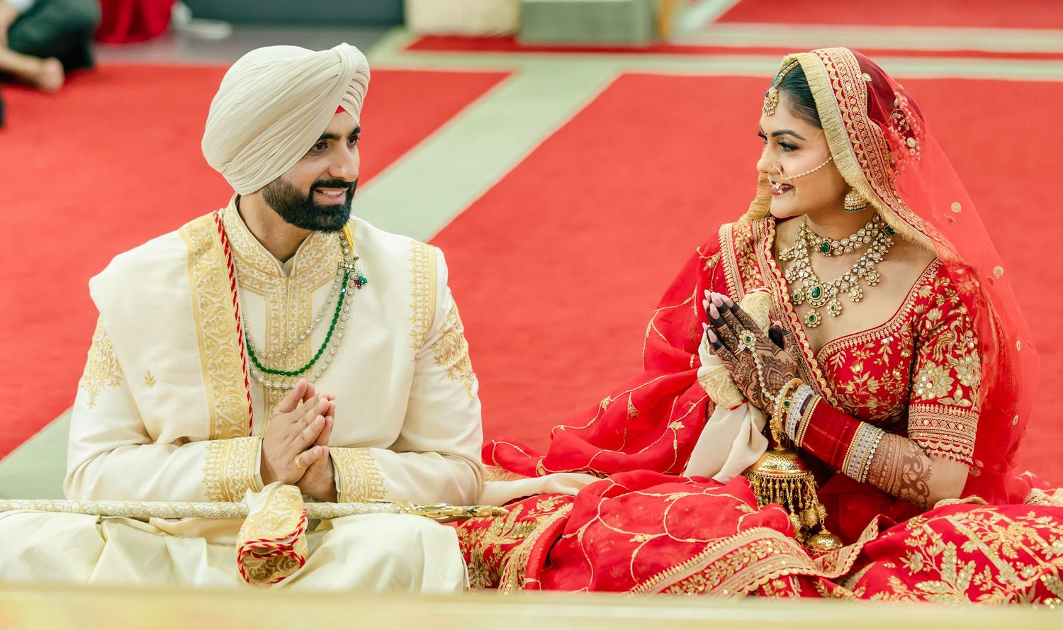 A traditional Sikh wedding ceremony moment captured with red and cream color scheme.