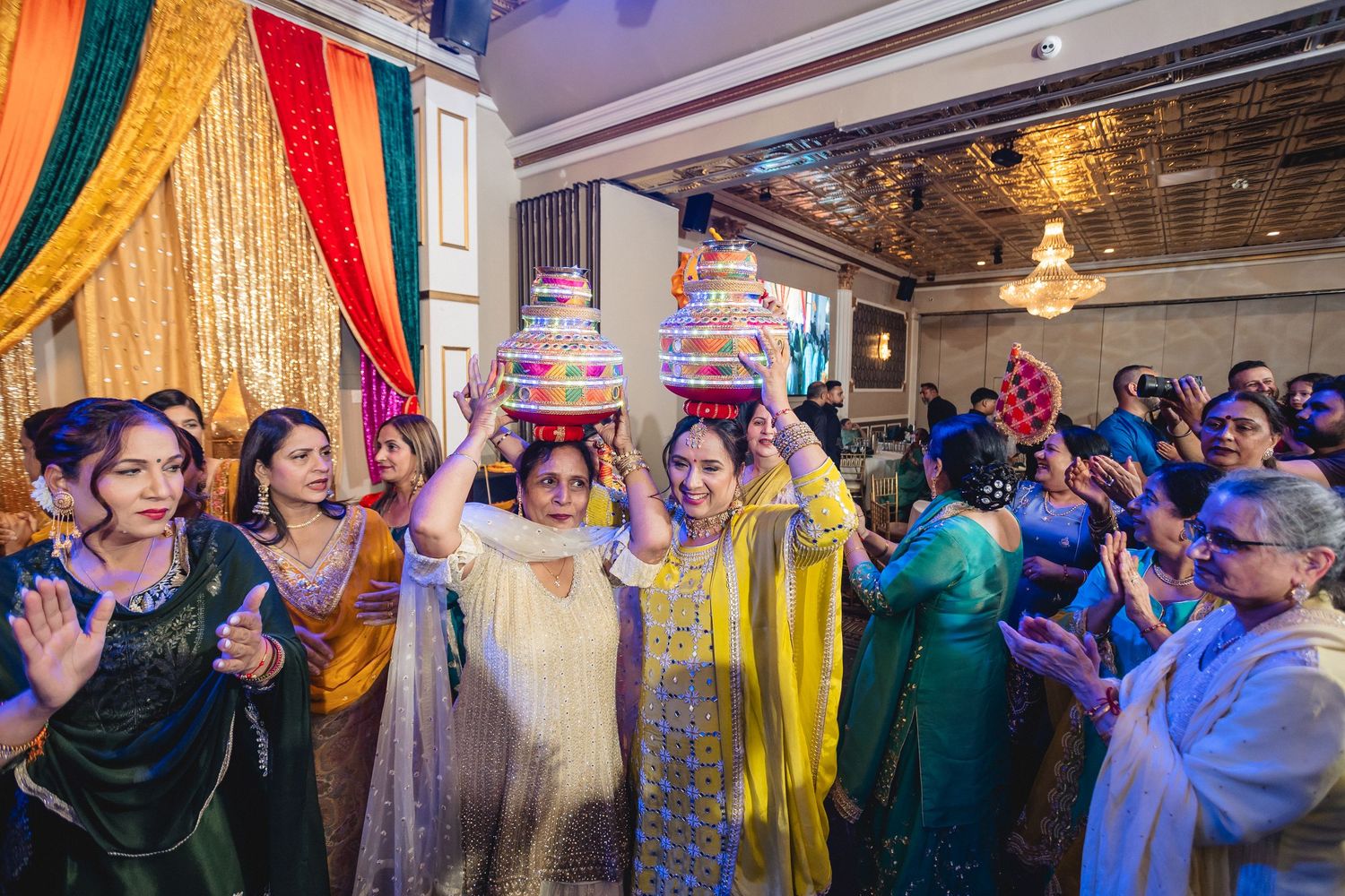 Wide shot of people dancing and celebrating under purple mood lighting at an indoor cultural event.