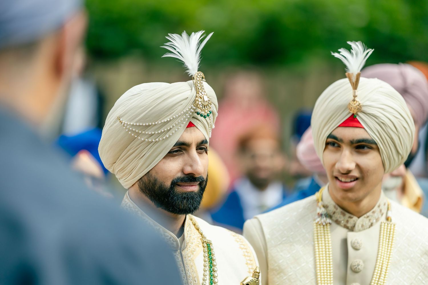 Outdoor wedding celebration with attendees wearing traditional Sikh turbans and formal attire.