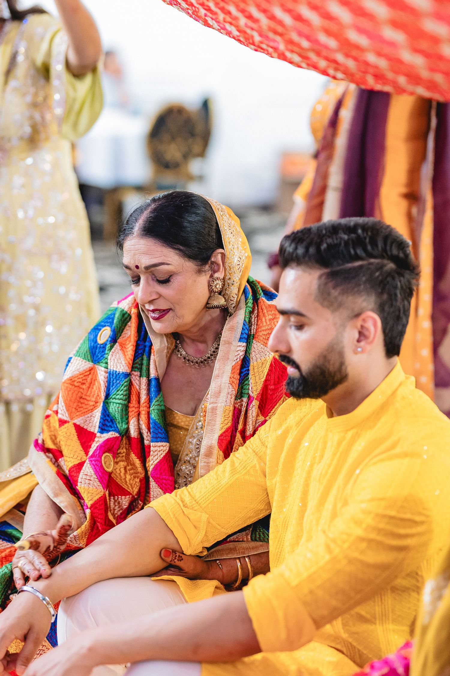 Couple in yellow traditional Indian wedding attire sharing a joyful moment during ceremony.