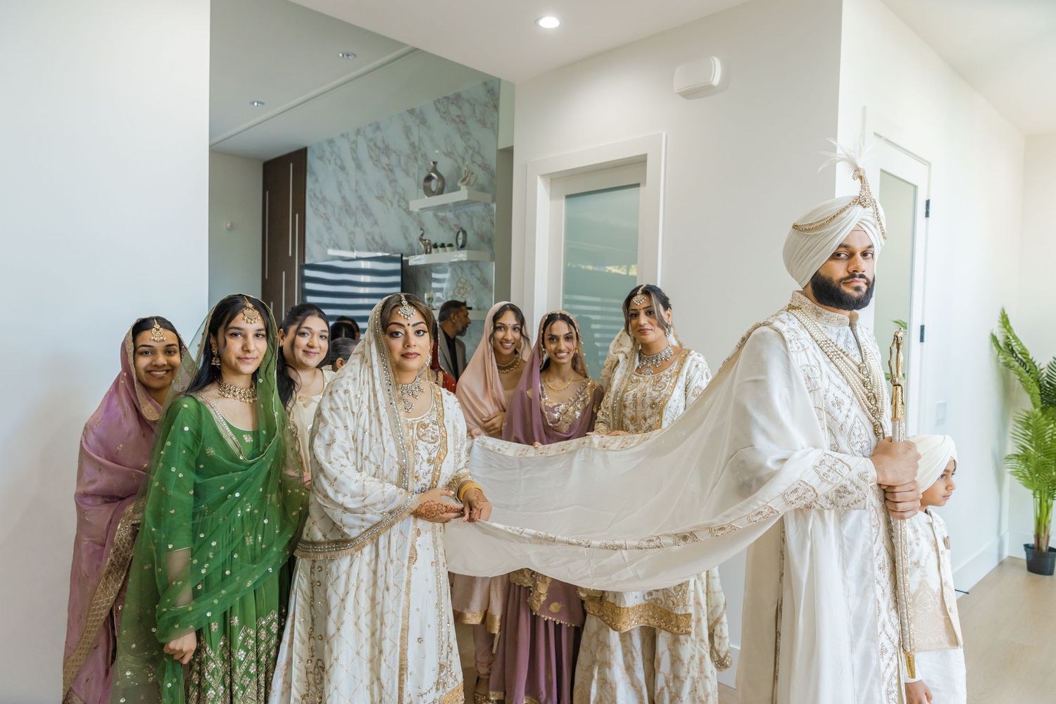 Wedding party members in pastel and white outfits posing together indoors.