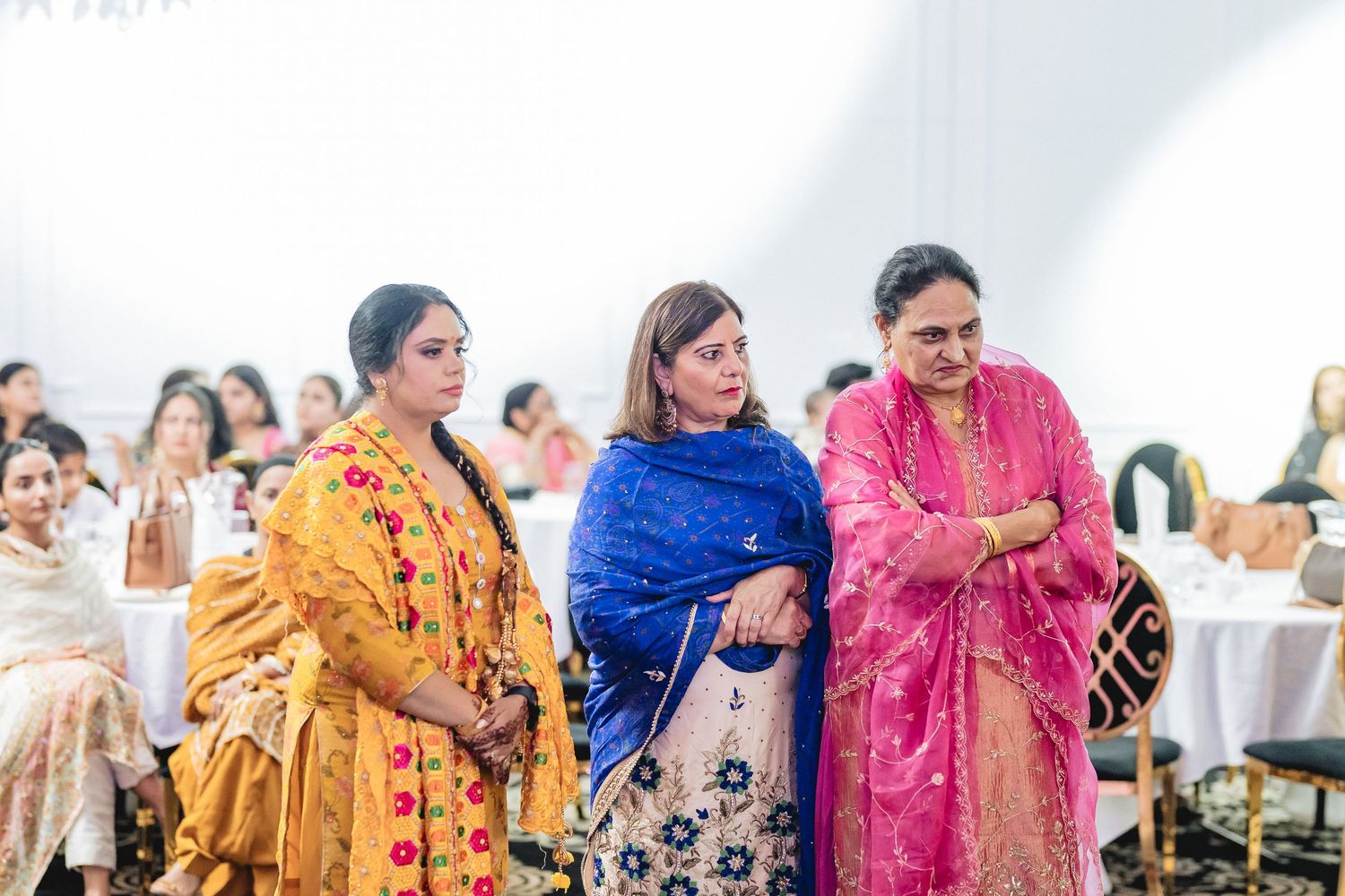 People wearing colorful traditional Indian and Sikh attire seated in rows at a cultural celebration.
