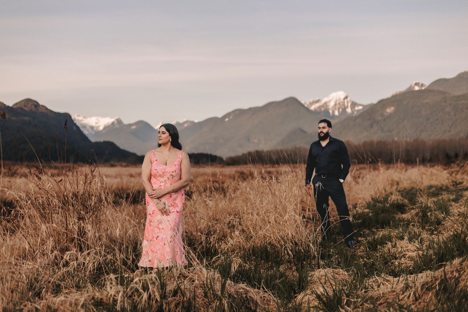 Scenic mountain landscape serves as backdrop for romantic photoshoot in golden field.