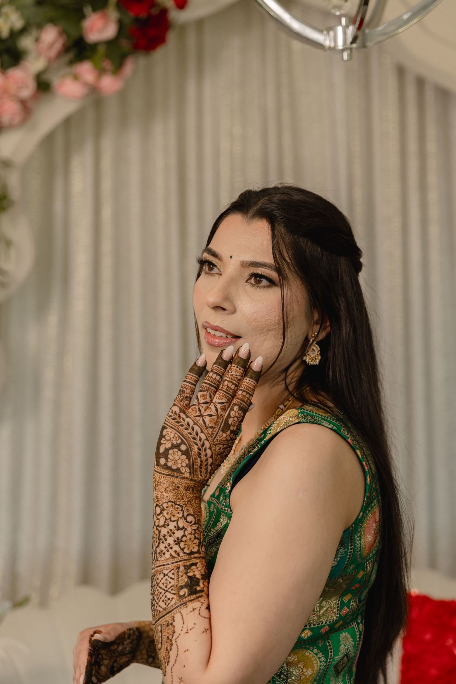Elegant green outfit with detailed henna mehndi designs on hands.