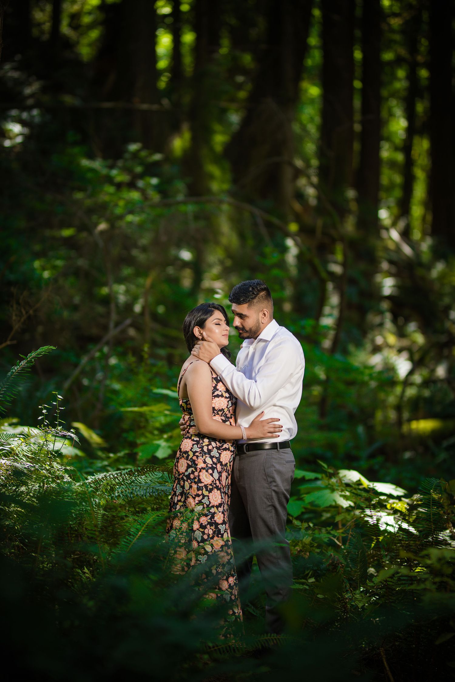 Intimate engagement photoshoot in a lush green forest setting.