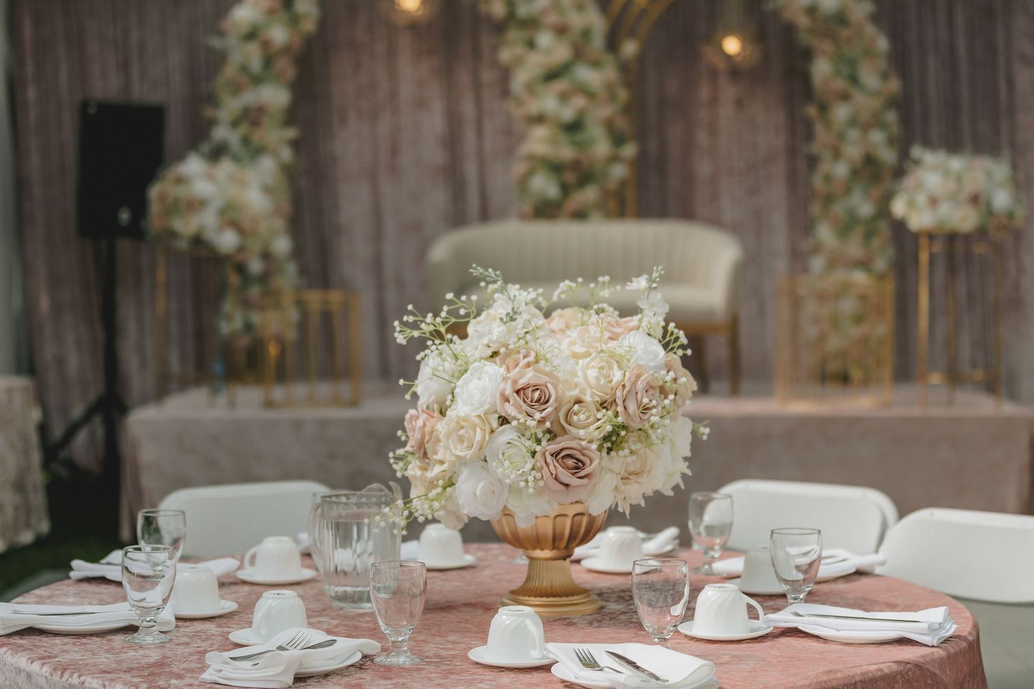 Elegant wedding reception tables set with white floral centerpieces and soft lighting.