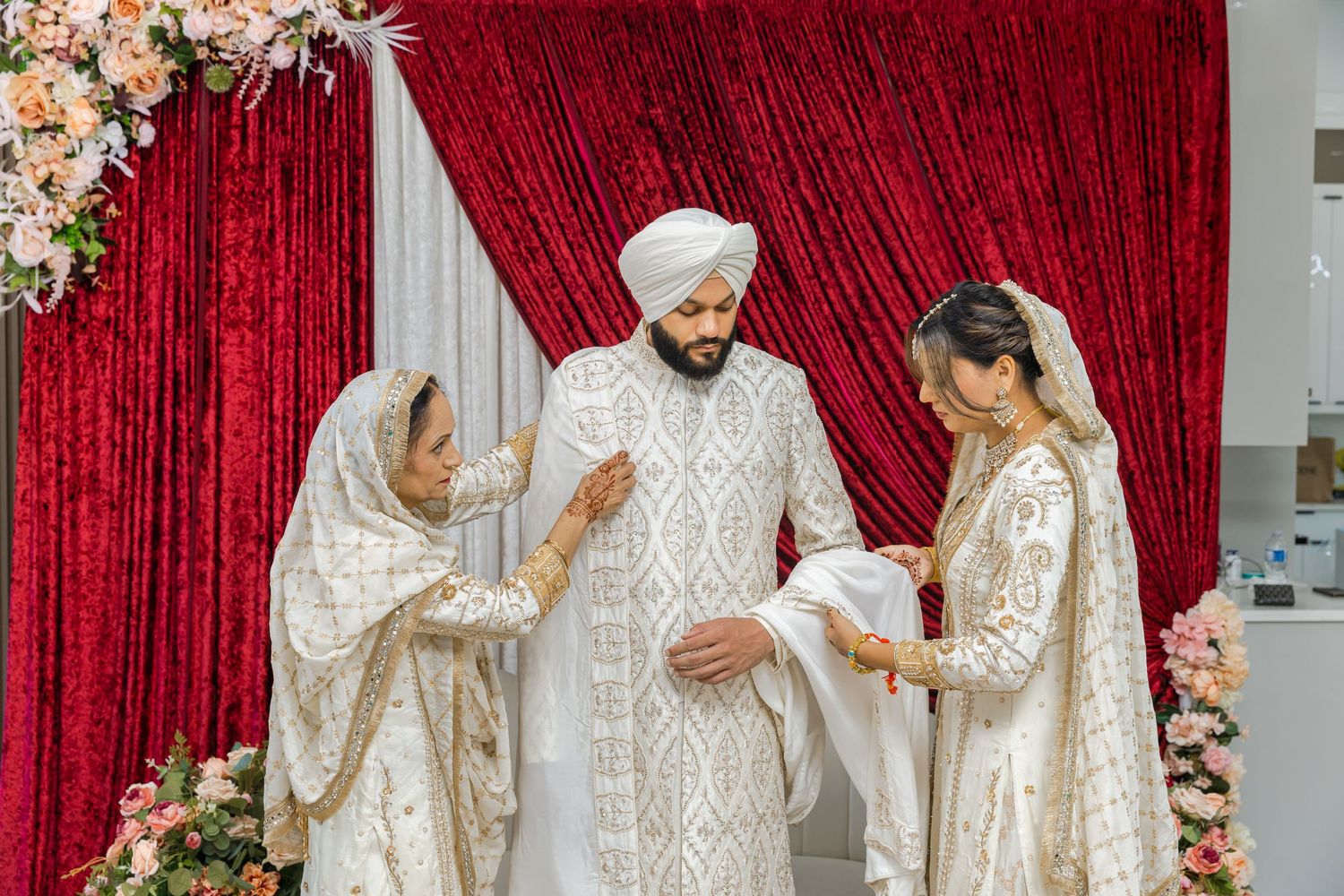 Traditional Sikh wedding ceremony with red backdrop and floral decorations.
