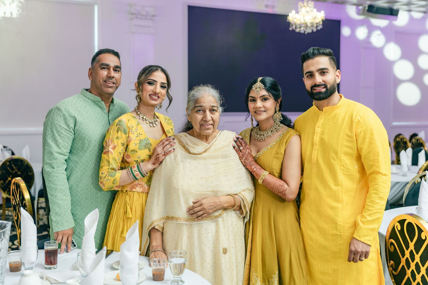 Wedding celebration with guests wearing coordinated yellow and green outfits in an elegantly decorated venue.