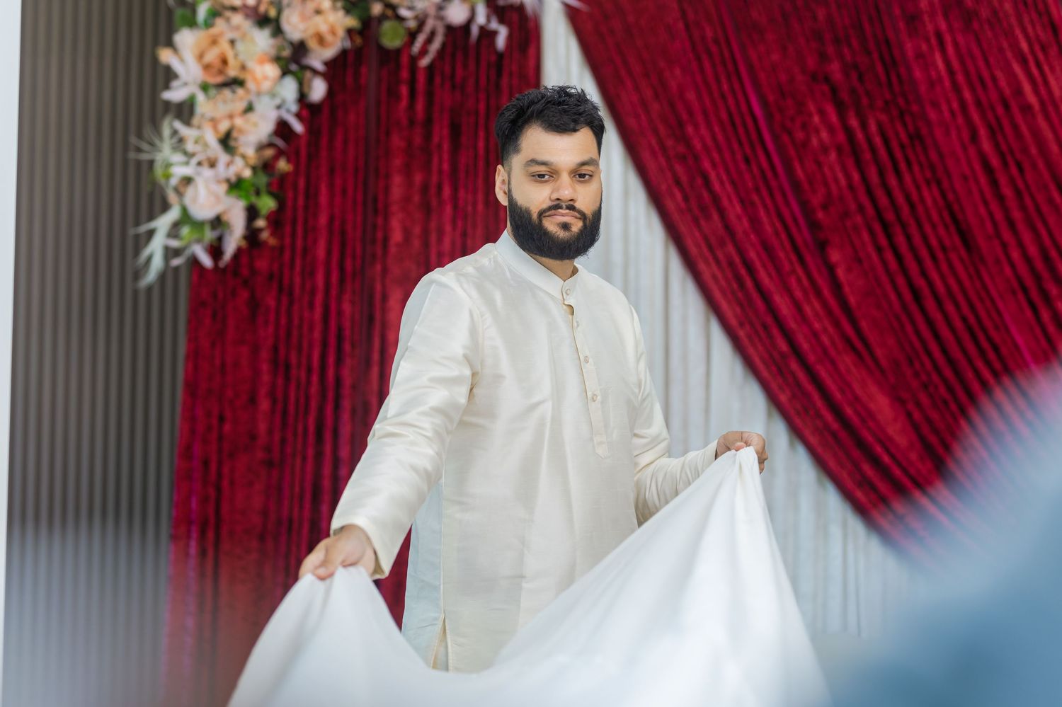 Wedding ceremony setup with red velvet curtains and floral decorations.