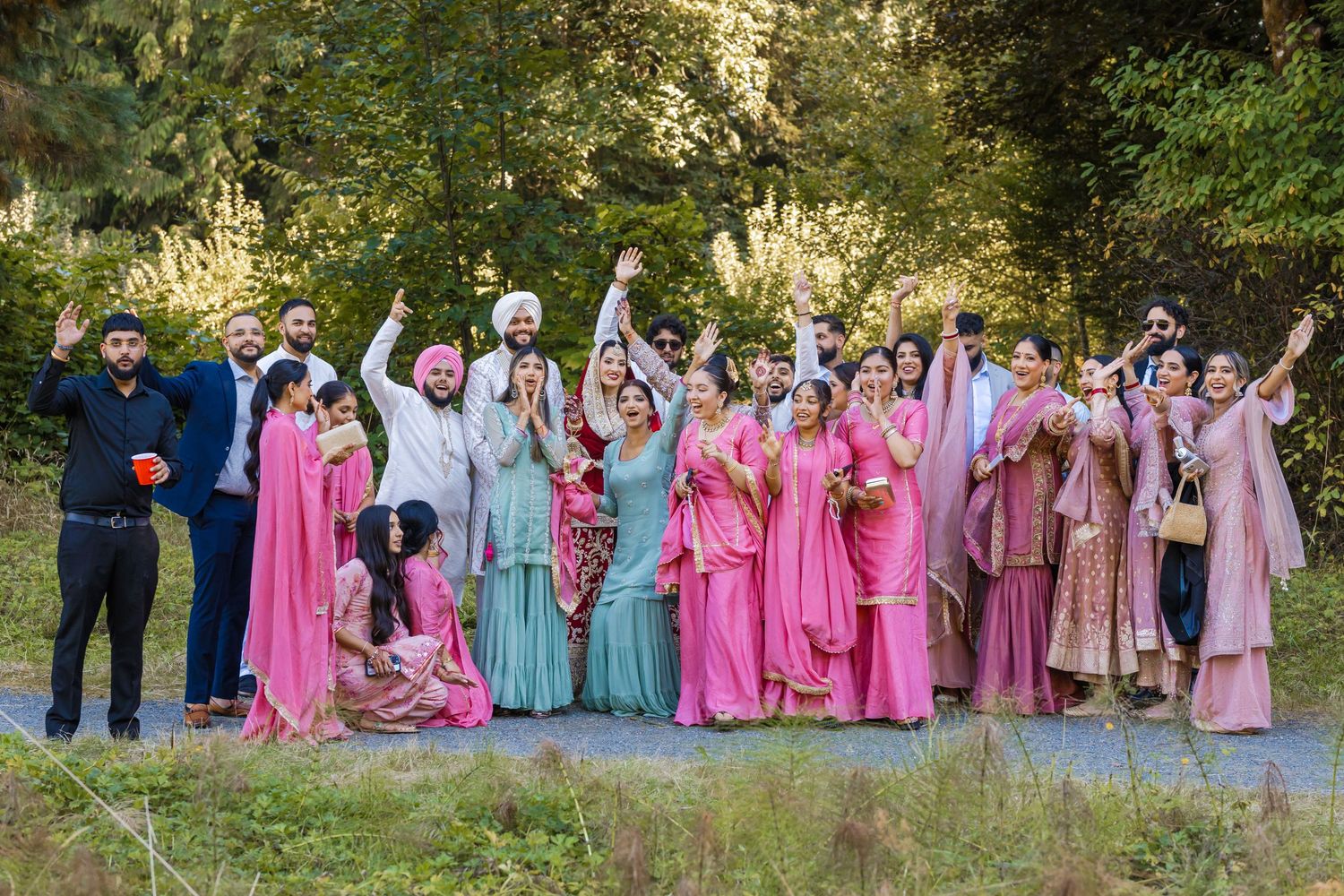 Wedding party group photo outdoors with bridesmaids in pink and blue dresses.