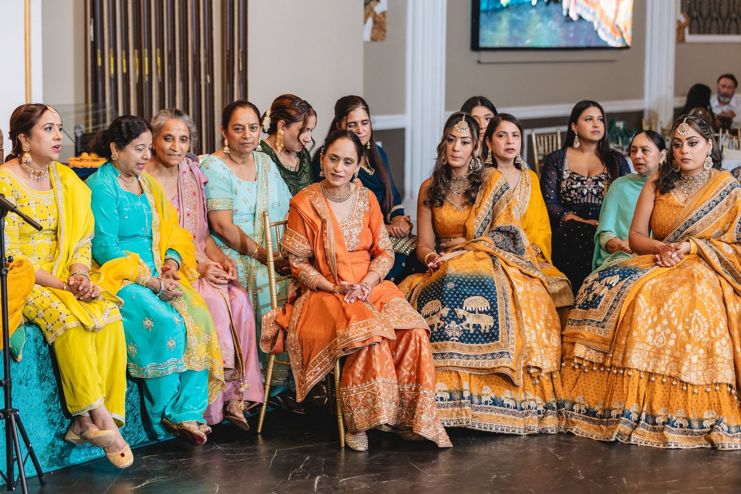 Guests in vibrant traditional outfits seated in rows at an Indian celebration.