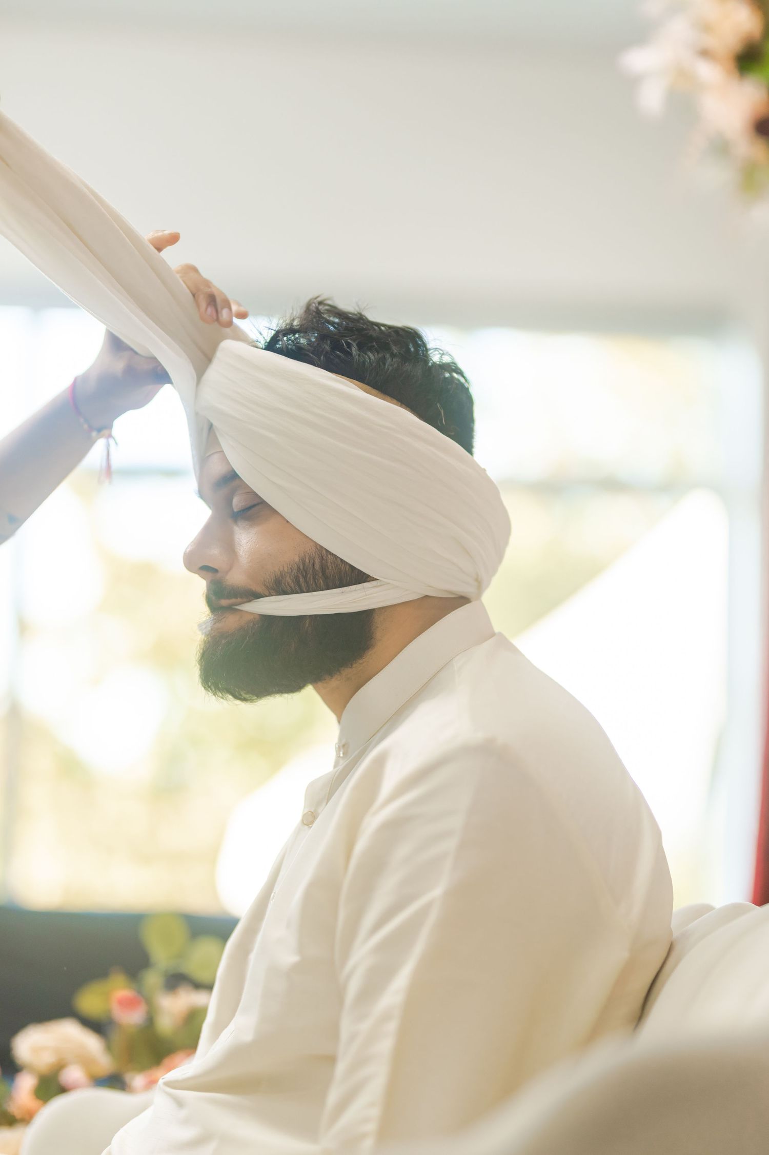 Traditional Sikh ceremony with attendees in white attire seated during religious gathering.