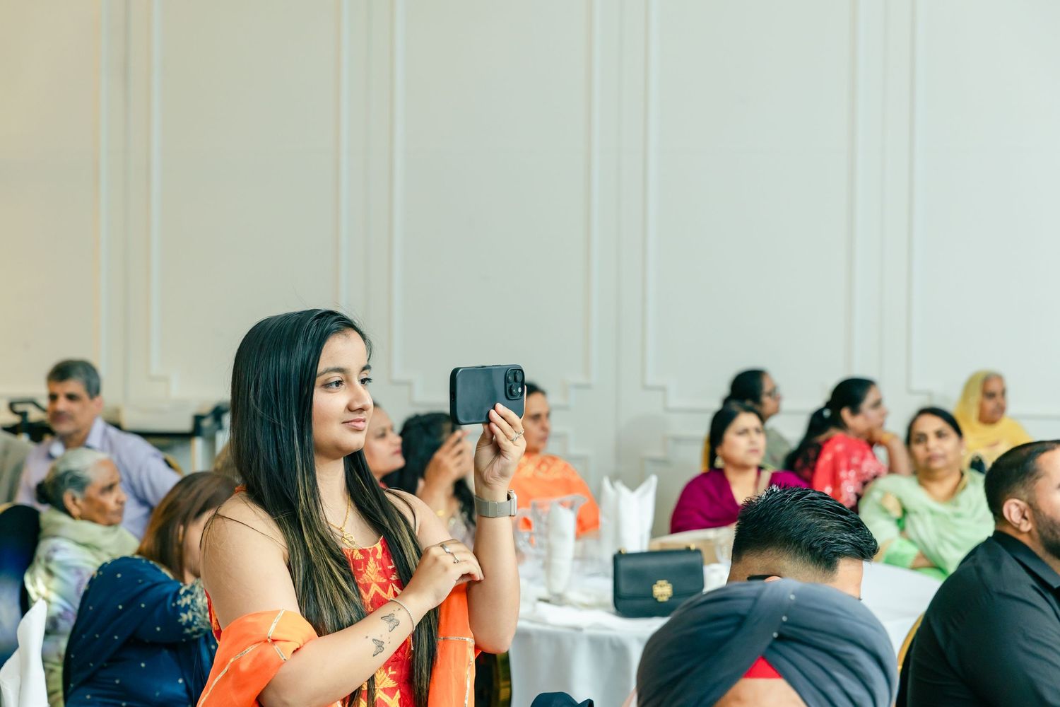 Guests celebrating joyfully at an indoor event with white curtains and decorative lighting.