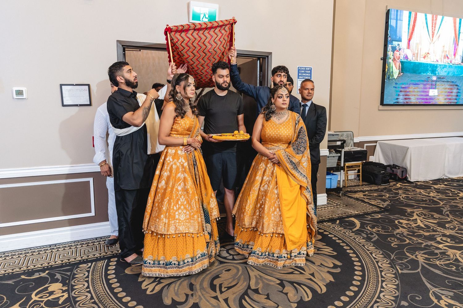 Performers in matching orange gowns pose for photos during what appears to be a wedding or formal event.