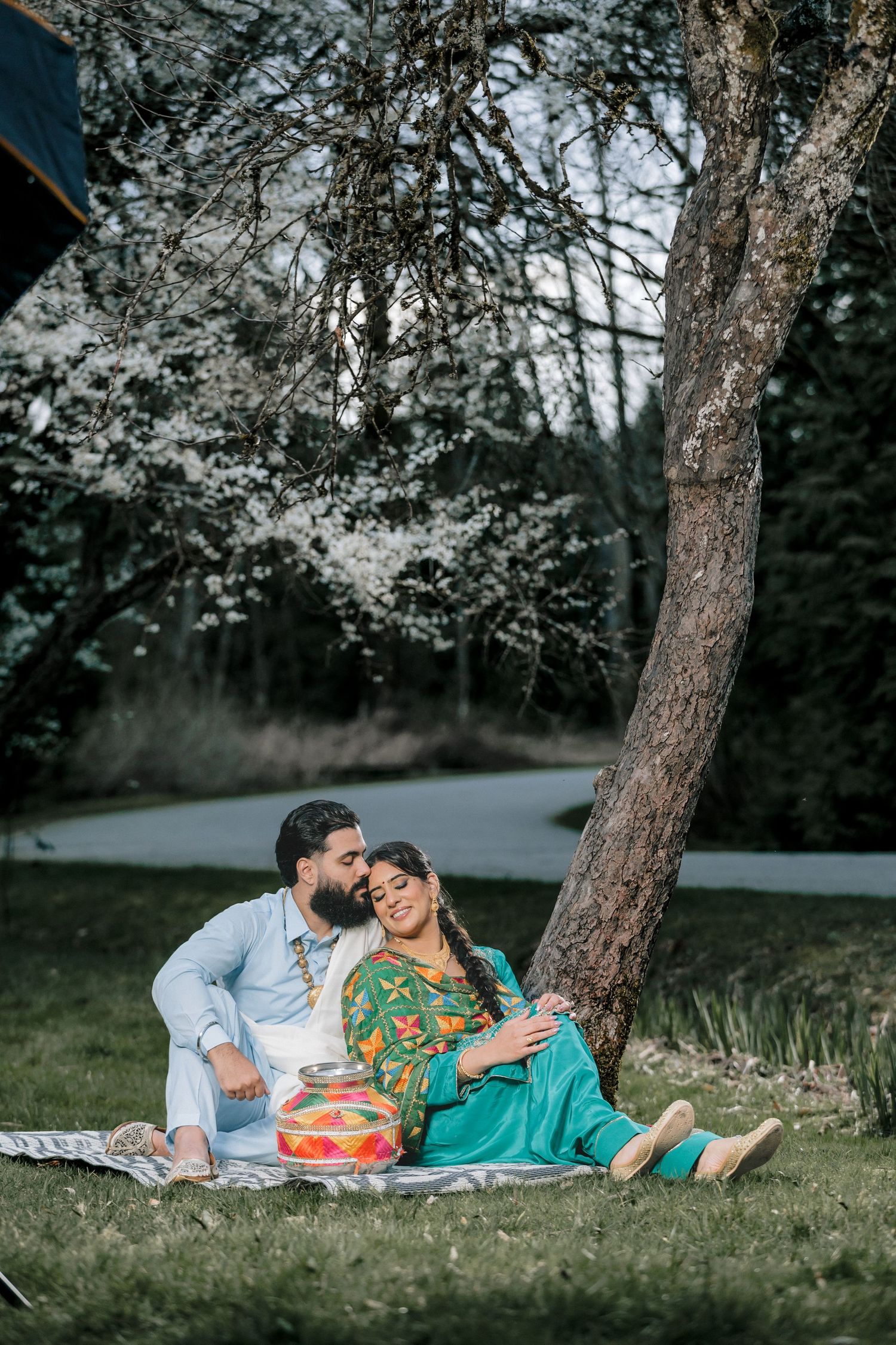 Romantic picnic scene under blooming trees with couple in coordinated outfits.
