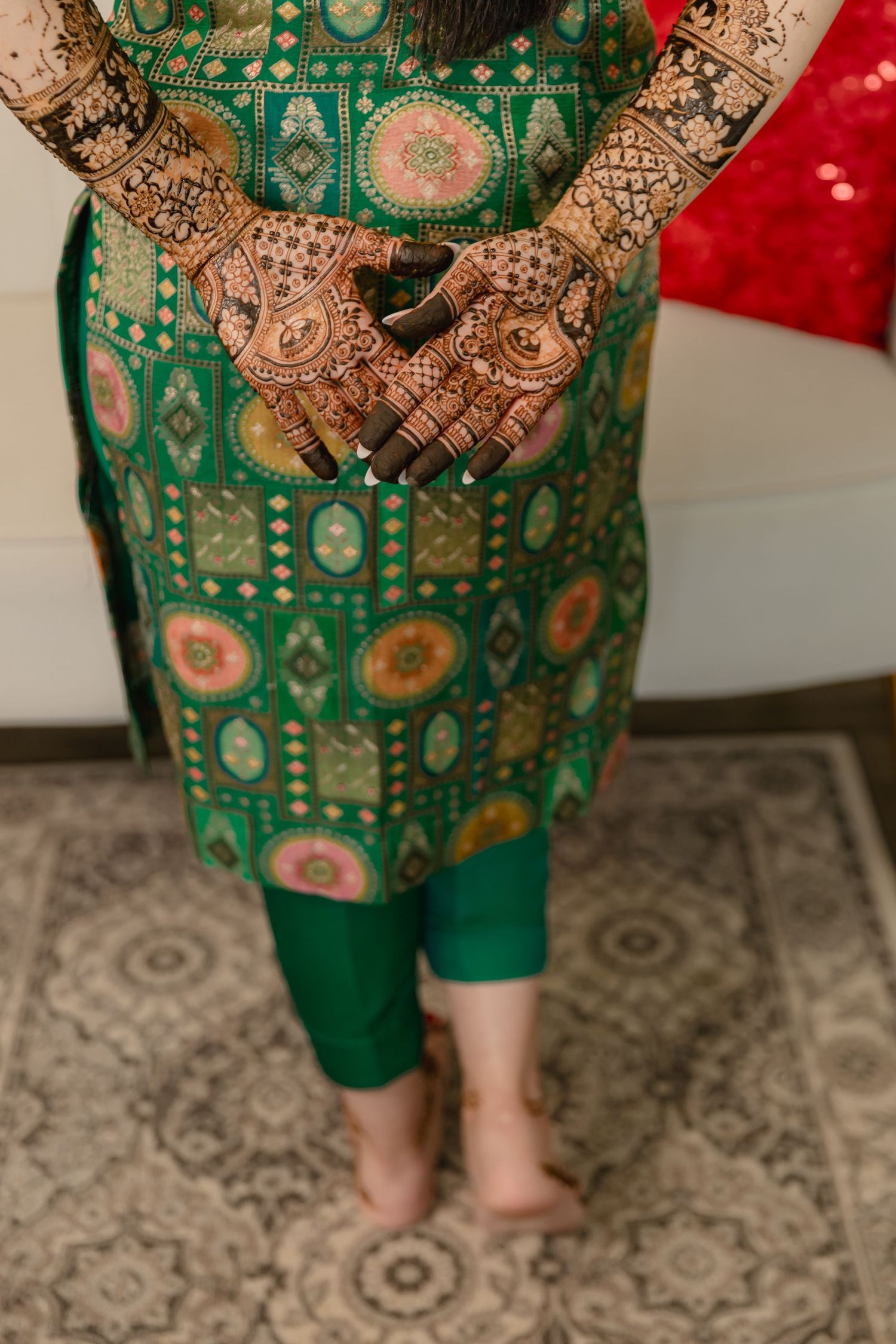 Green and gold embroidered traditional outfit with detailed patterns. Mehndi hands