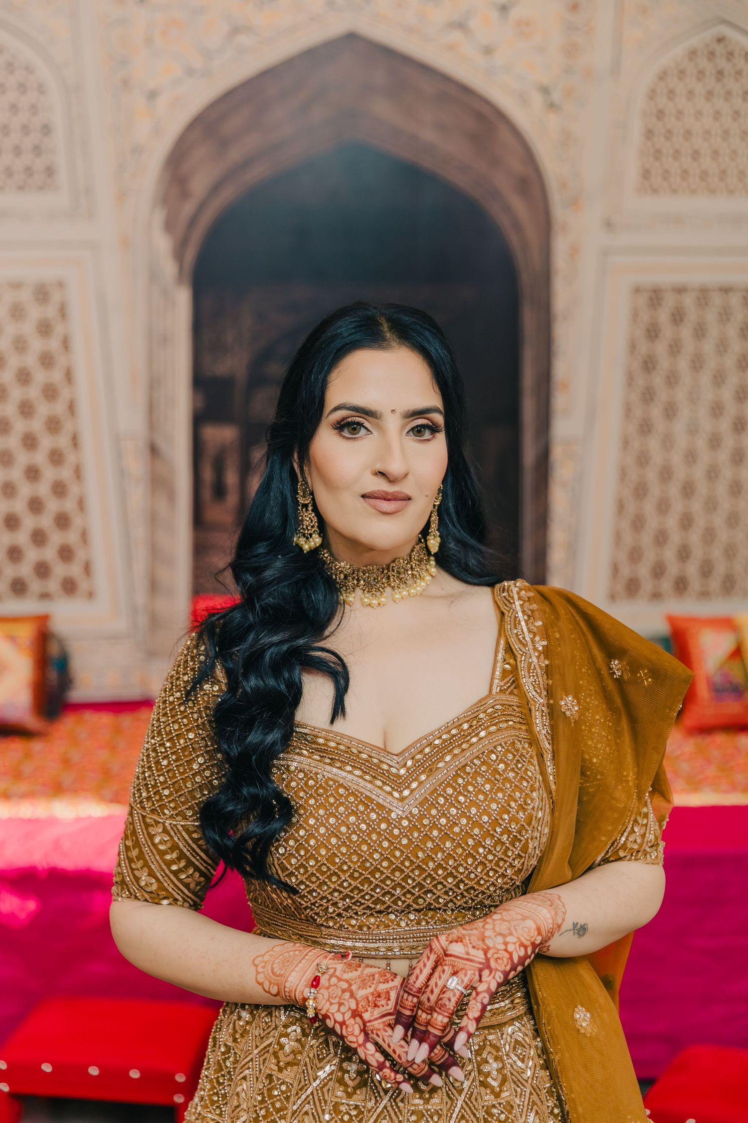 Traditional Indian bridal attire featuring an ornate gold embellished dress and jewelry.