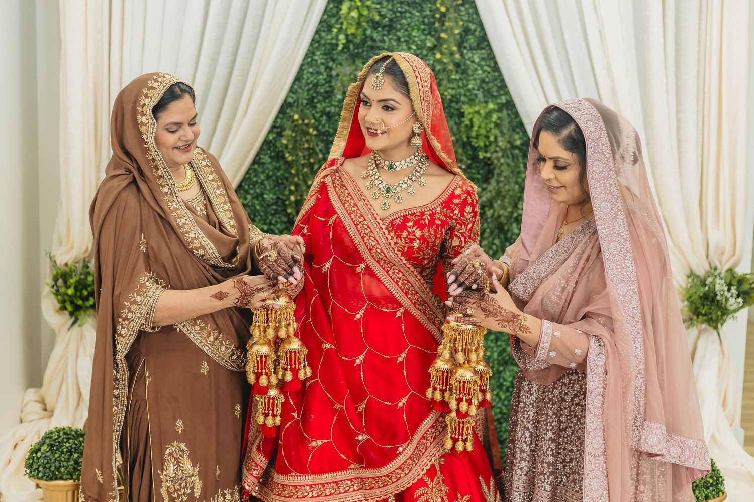 Wedding ceremony gathering with guests in traditional Indian attire against white draped backdrop.
