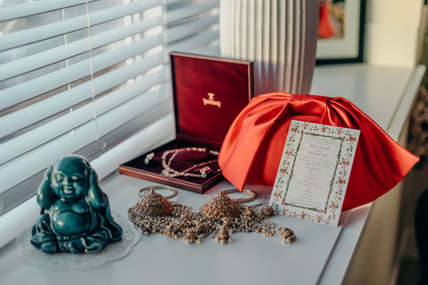 Wedding accessories including red shoes, jewelry, and documents arranged on windowsill.
