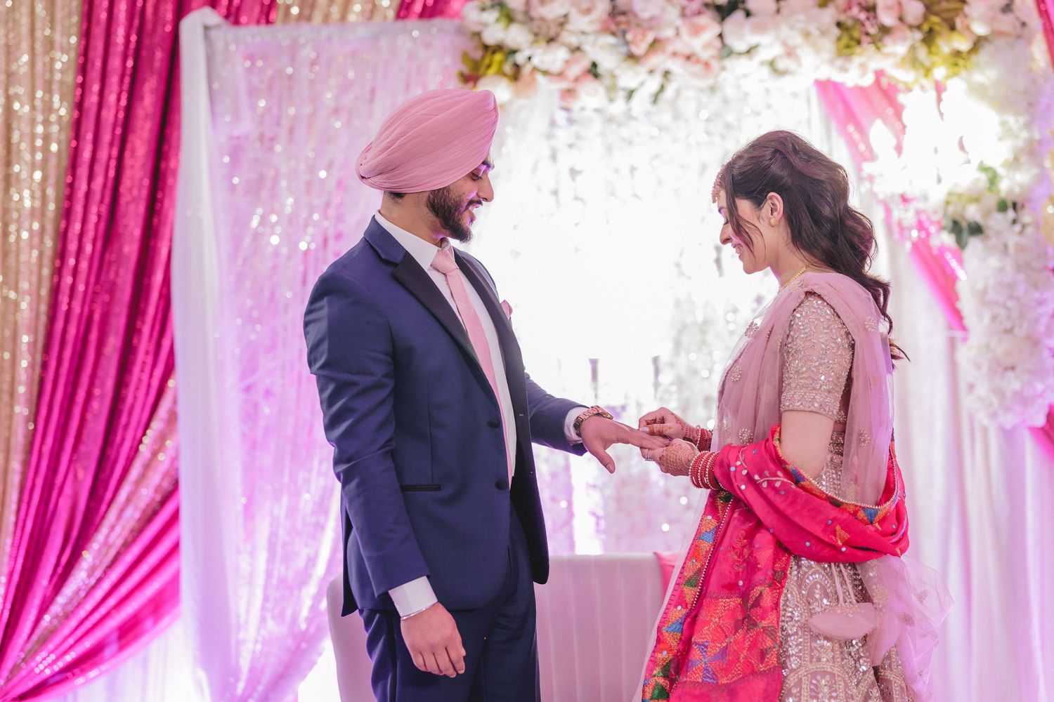 Traditional ring exchange ceremony under pink and white floral wedding decor.