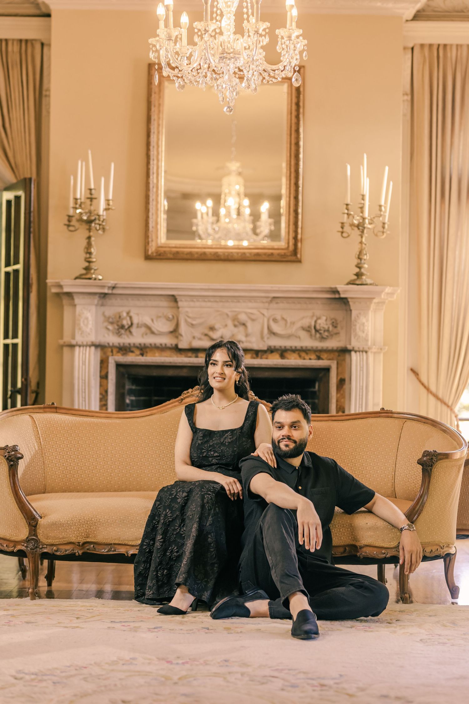 A glamorous couple's photoshoot in an elegant room with crystal chandeliers and period furniture.