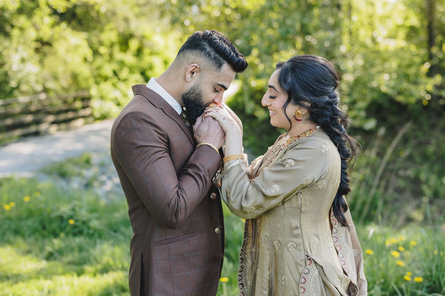 Couple embracing in a natural outdoor setting with green foliage in the background.