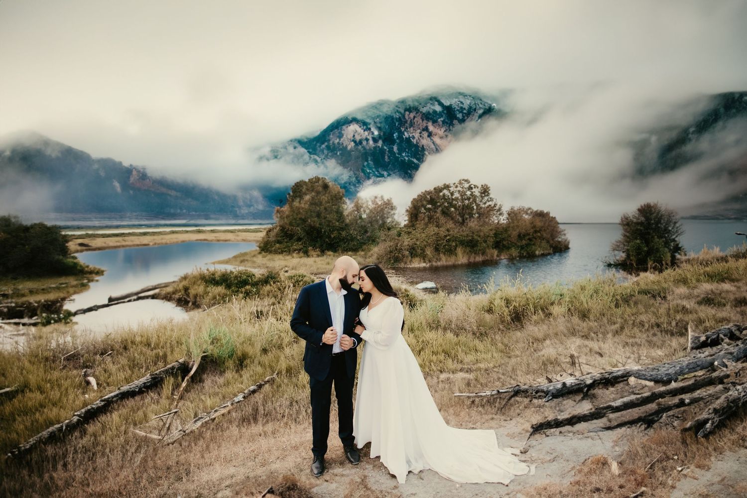 Dramatic wedding photos against misty mountain and lake landscape.