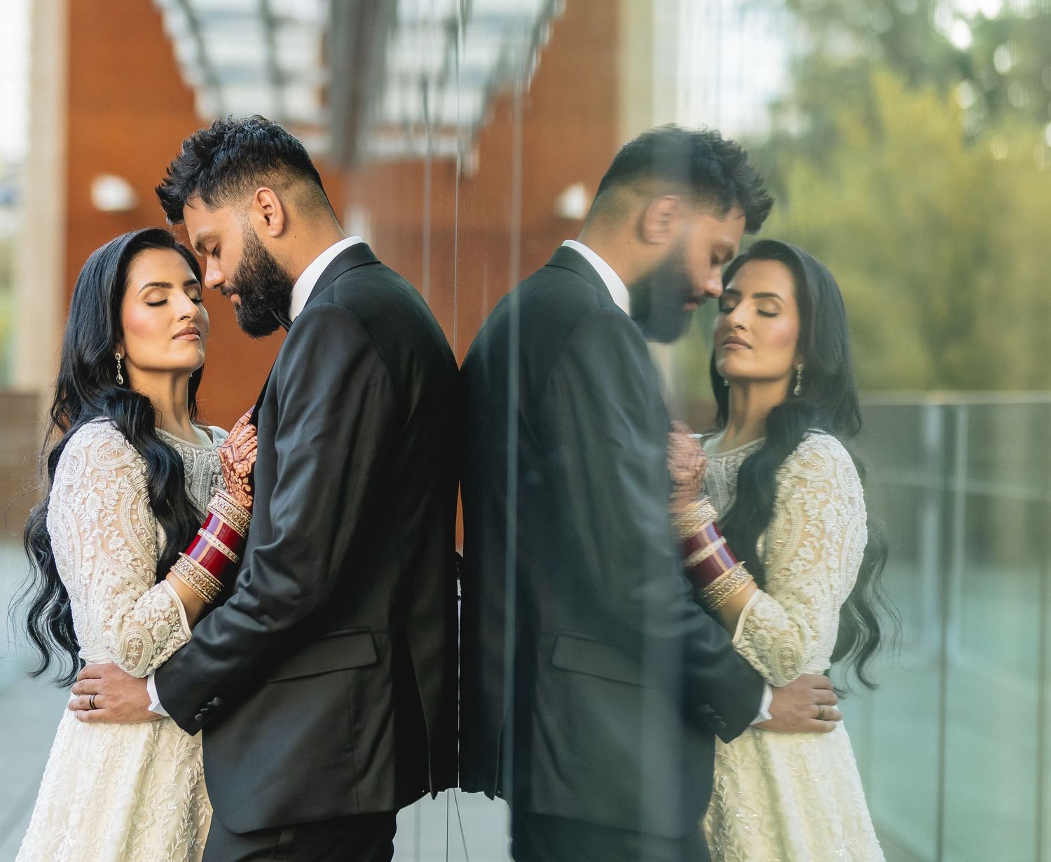 An elegant indoor wedding photoshoot with reflective glass panels creating mirror-like effects.